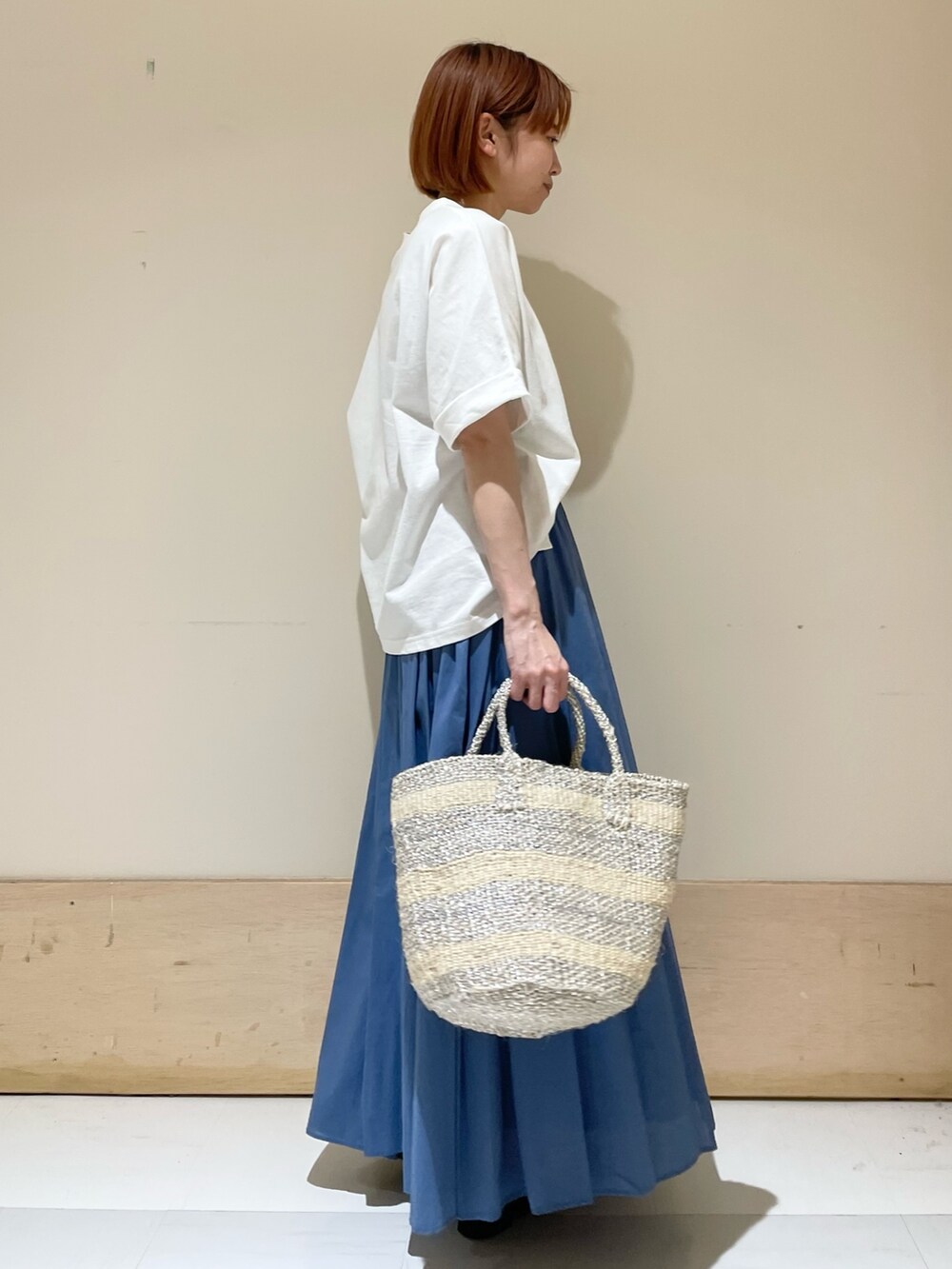 ホワイト系のTシャツ/カットソー、ブルー系のスカート、ホワイト系のハンドバッグを着用したレディースの夏コーディネートの3枚目の写真
