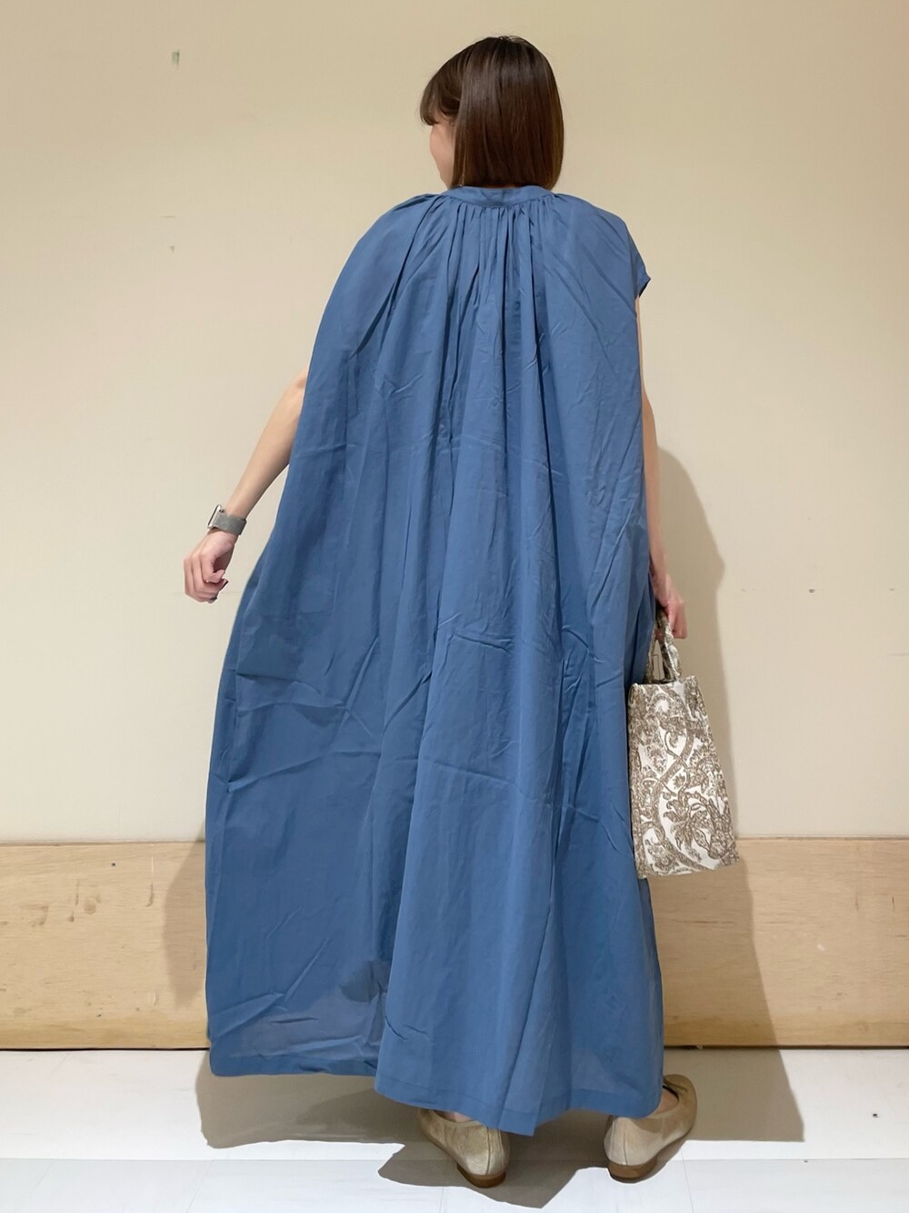 ブルー系のワンピース、ベージュ系のトートバッグ、ゴールド系のパンプスを着用したレディースの夏コーディネートの6枚目の写真