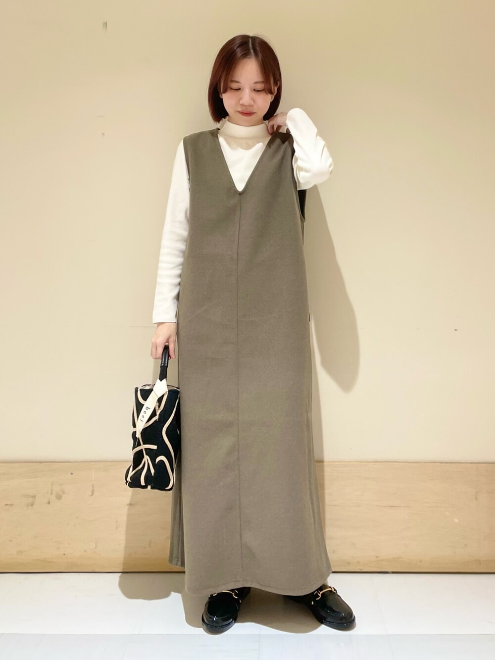 ブラウン系のワンピース、ホワイト系のTシャツ/カットソー、ブラック系のショルダーバッグを着用したレディースの秋コーディネートの2枚目の写真