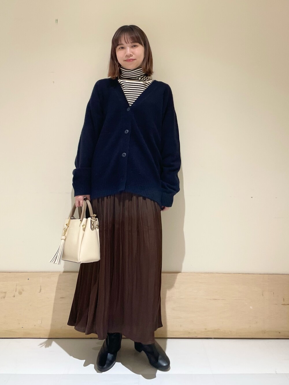 ブルー系のカーディガン/ボレロ、ホワイト系のニット/セーター、ブラウン系のスカートを着用したレディースの冬コーディネートの2枚目の写真