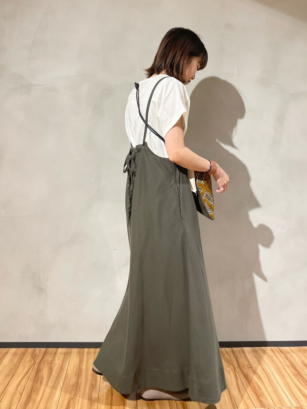 グリーン系のスカート、ホワイト系のTシャツ/カットソー、ブラック系のショルダーバッグを着用したレディースの秋コーディネートの3枚目の写真