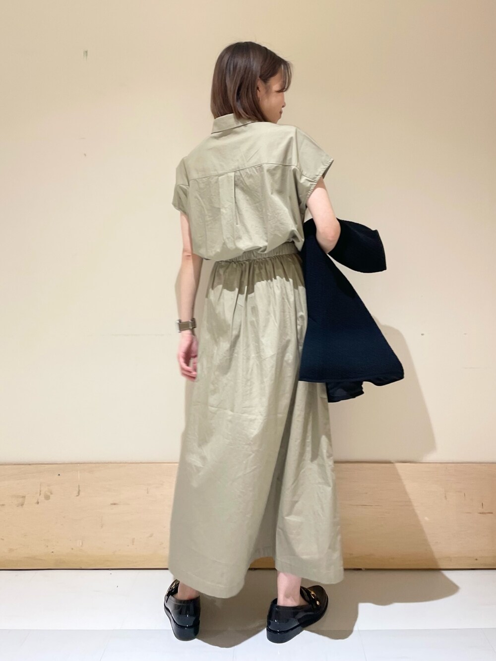 グレー系のショルダーバッグ、ブラック系のノーカラージャケット、ベージュ系のワンピースを着用したレディースの秋コーディネートの9枚目の写真