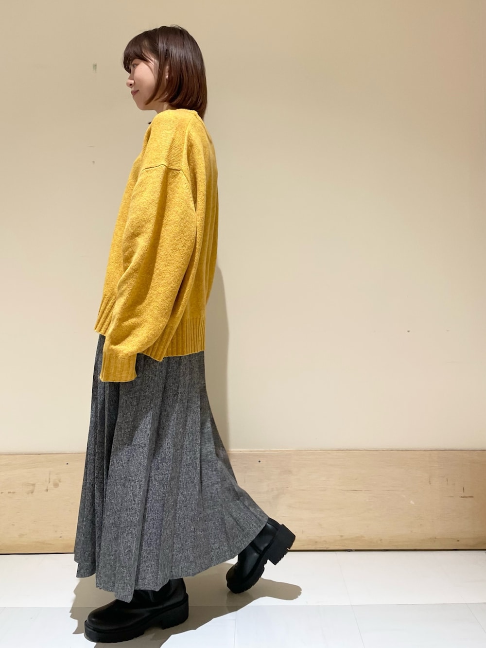 イエロー系のニット/セーター、ブルー系のスカート、ブラック系のブーツを着用したレディースの冬コーディネートの5枚目の写真