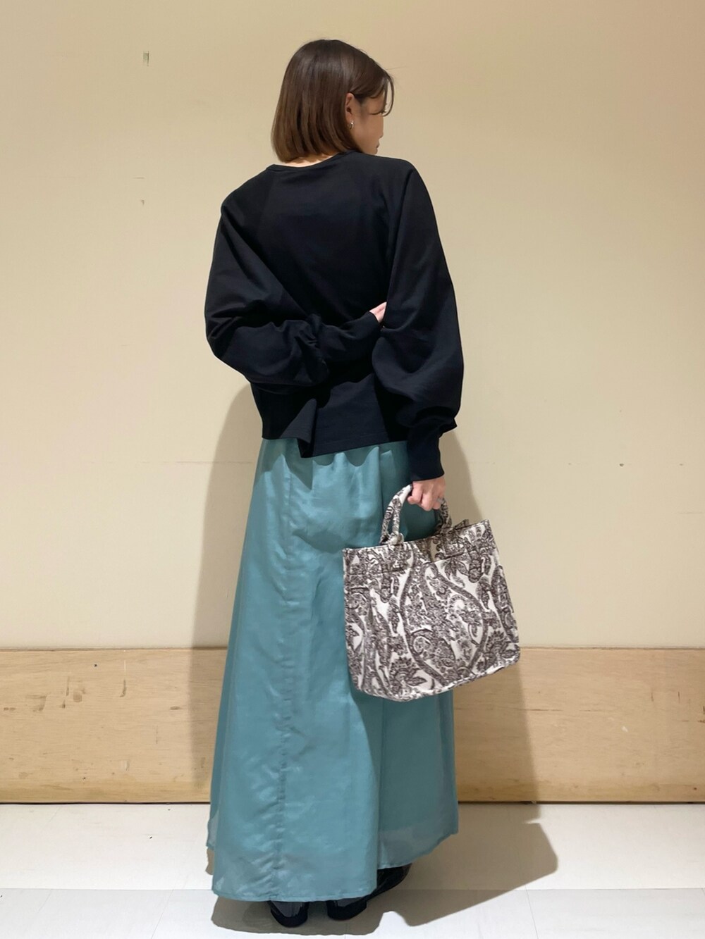 ブラック系のTシャツ/カットソー、グリーン系のスカート、ブラウン系のトートバッグを着用したレディースの秋コーディネートの8枚目の写真