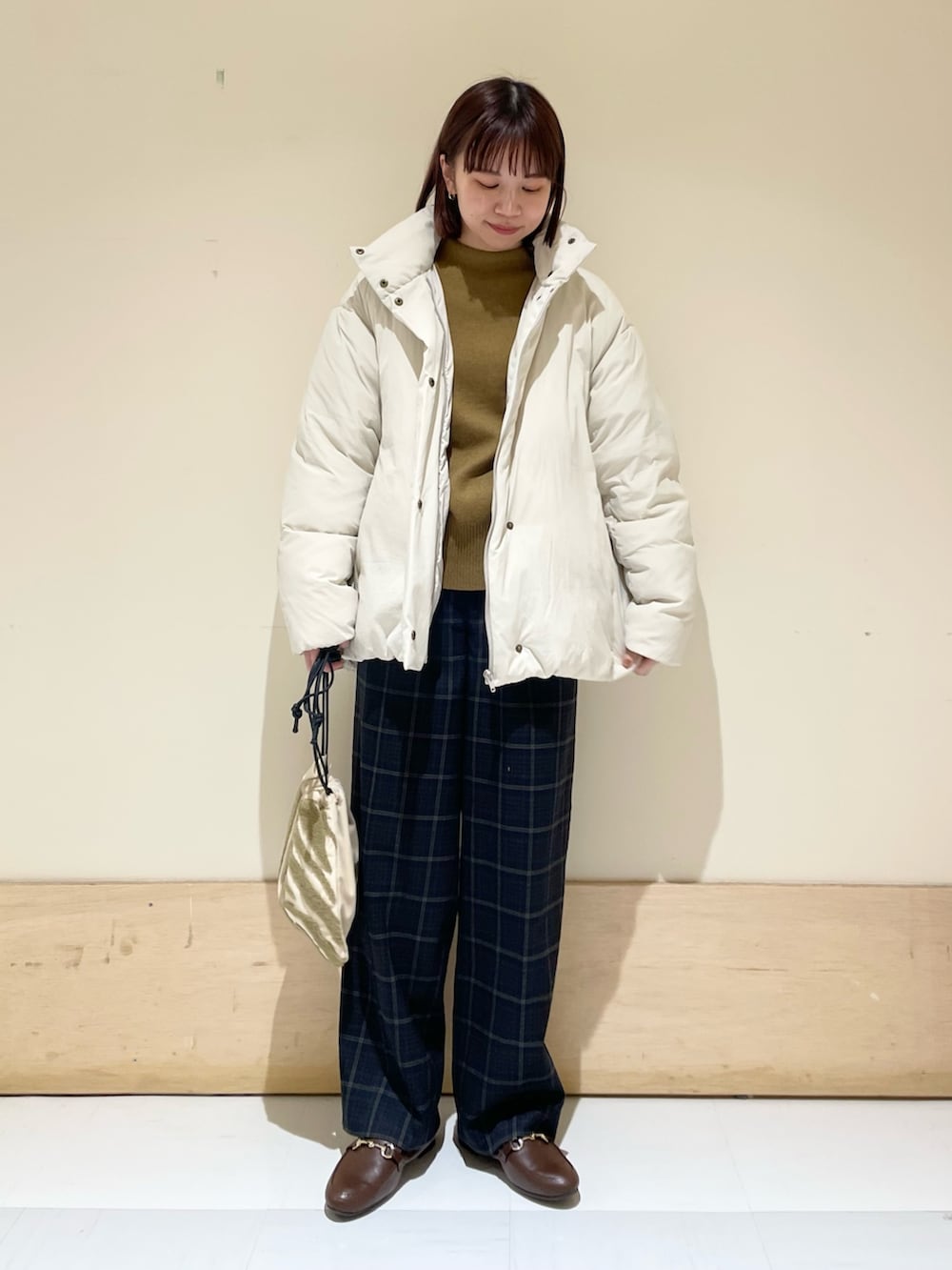 グリーン系のニット/セーター、ホワイト系のダウンジャケット/コート、ブラウン系のローファーを着用したレディースの秋コーディネートの2枚目の写真