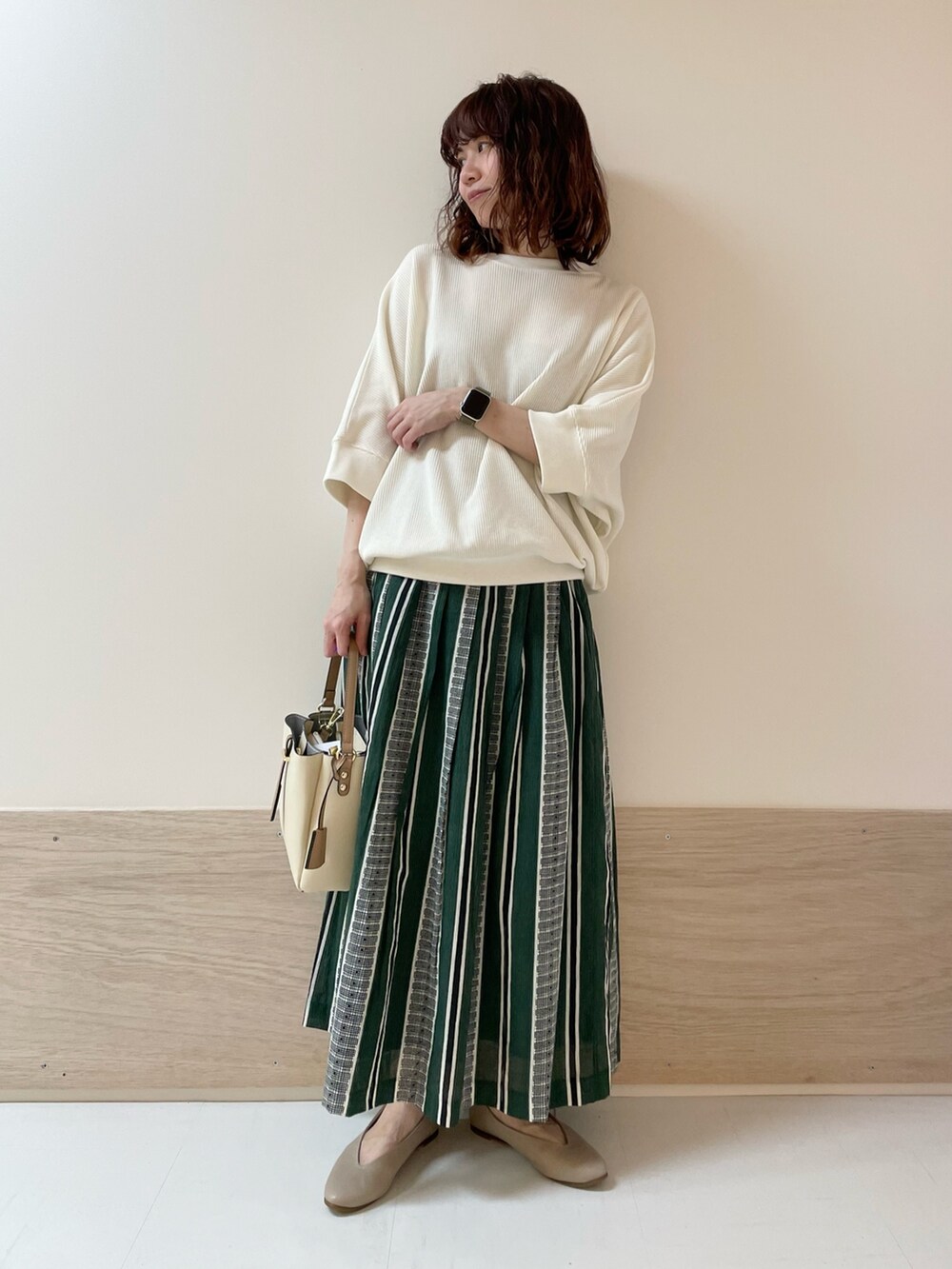 ホワイト系のTシャツ/カットソー、グリーン系のスカート、ベージュ系のパンプスを着用したレディースの春コーディネートの2枚目の写真