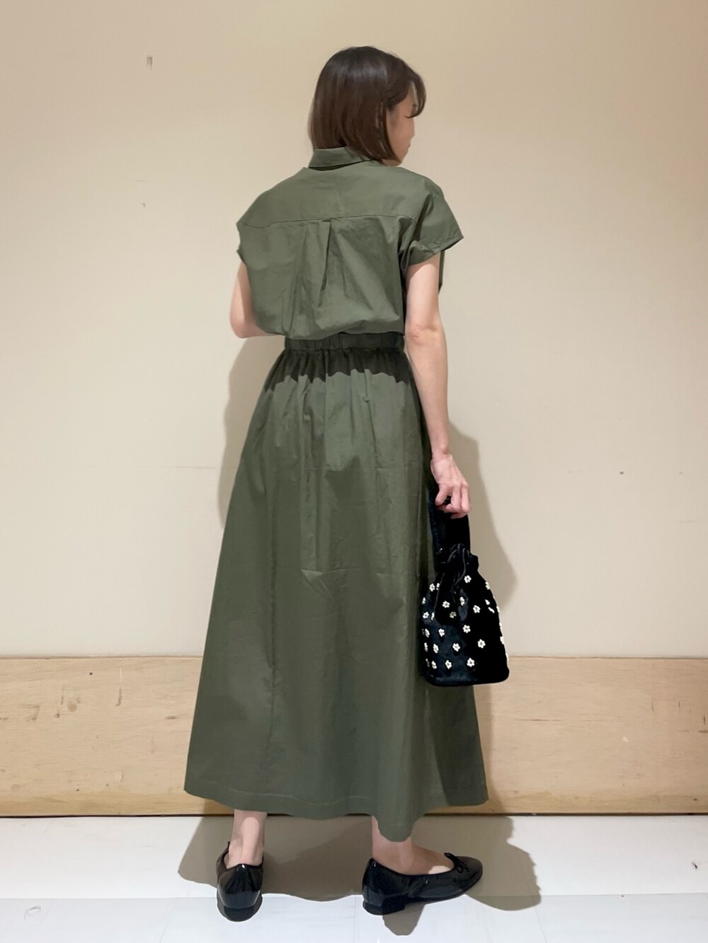 ブラック系のパンプス、ベージュ系のハンドバッグ、グリーン系のワンピースを着用したレディースの夏コーディネートの5枚目の写真