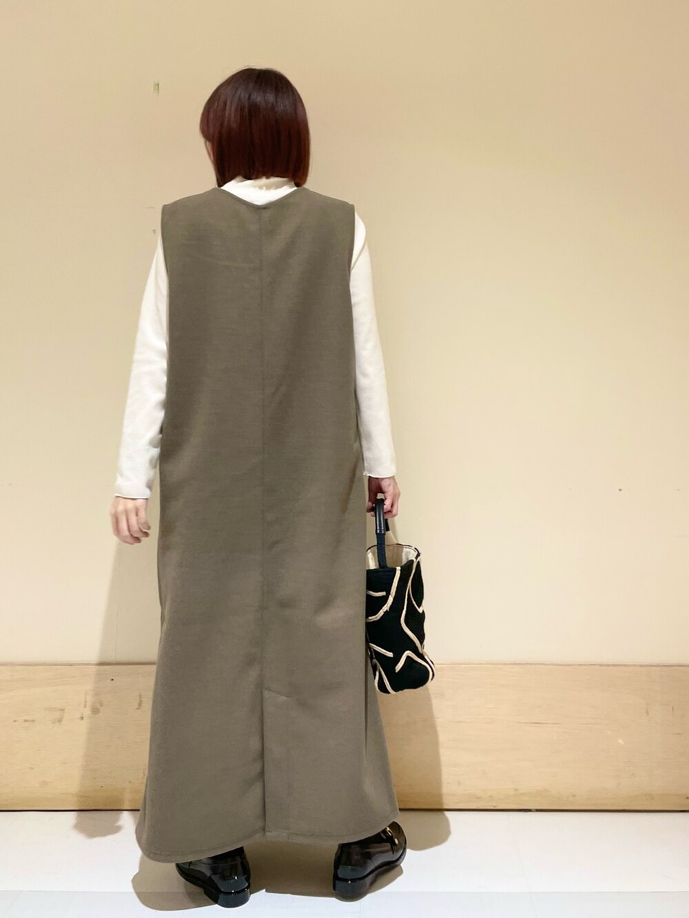 ブラウン系のワンピース、ホワイト系のTシャツ/カットソー、ブラック系のショルダーバッグを着用したレディースの秋コーディネートの6枚目の写真