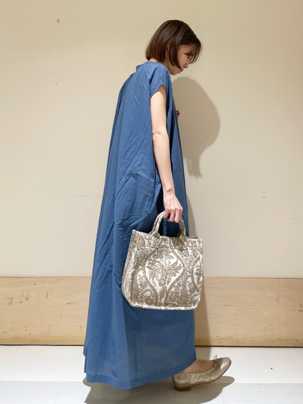 ブルー系のワンピース、ベージュ系のトートバッグ、ゴールド系のパンプスを着用したレディースの夏コーディネートの4枚目の写真