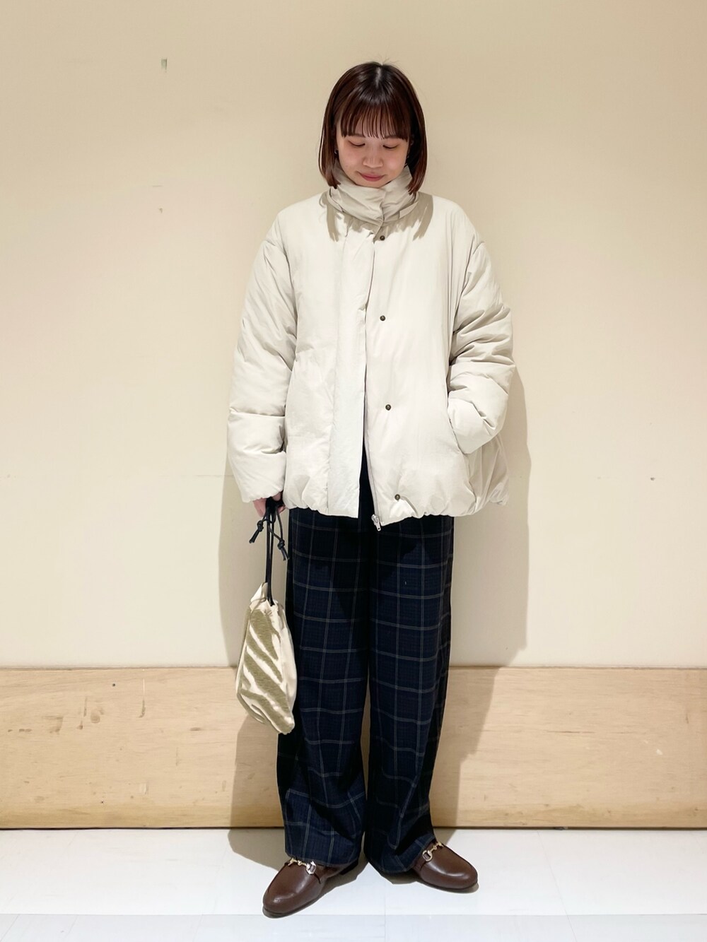 グリーン系のニット/セーター、ホワイト系のダウンジャケット/コート、ブラウン系のローファーを着用したレディースの秋コーディネートの9枚目の写真