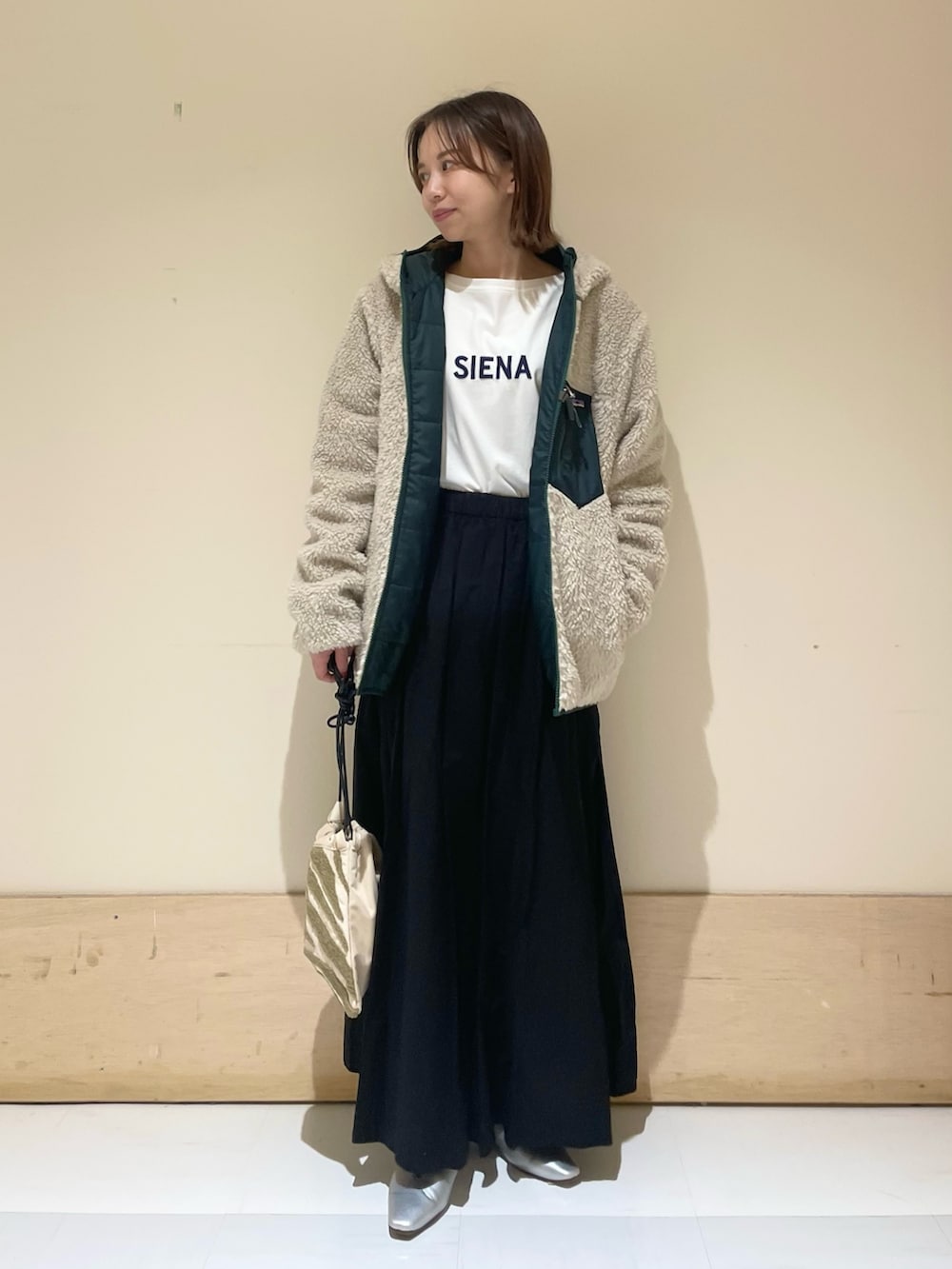 シルバー系のパンプス、ブルー系のTシャツ/カットソー、ベージュ系のハンドバッグを着用したレディースの秋コーディネートの2枚目の写真