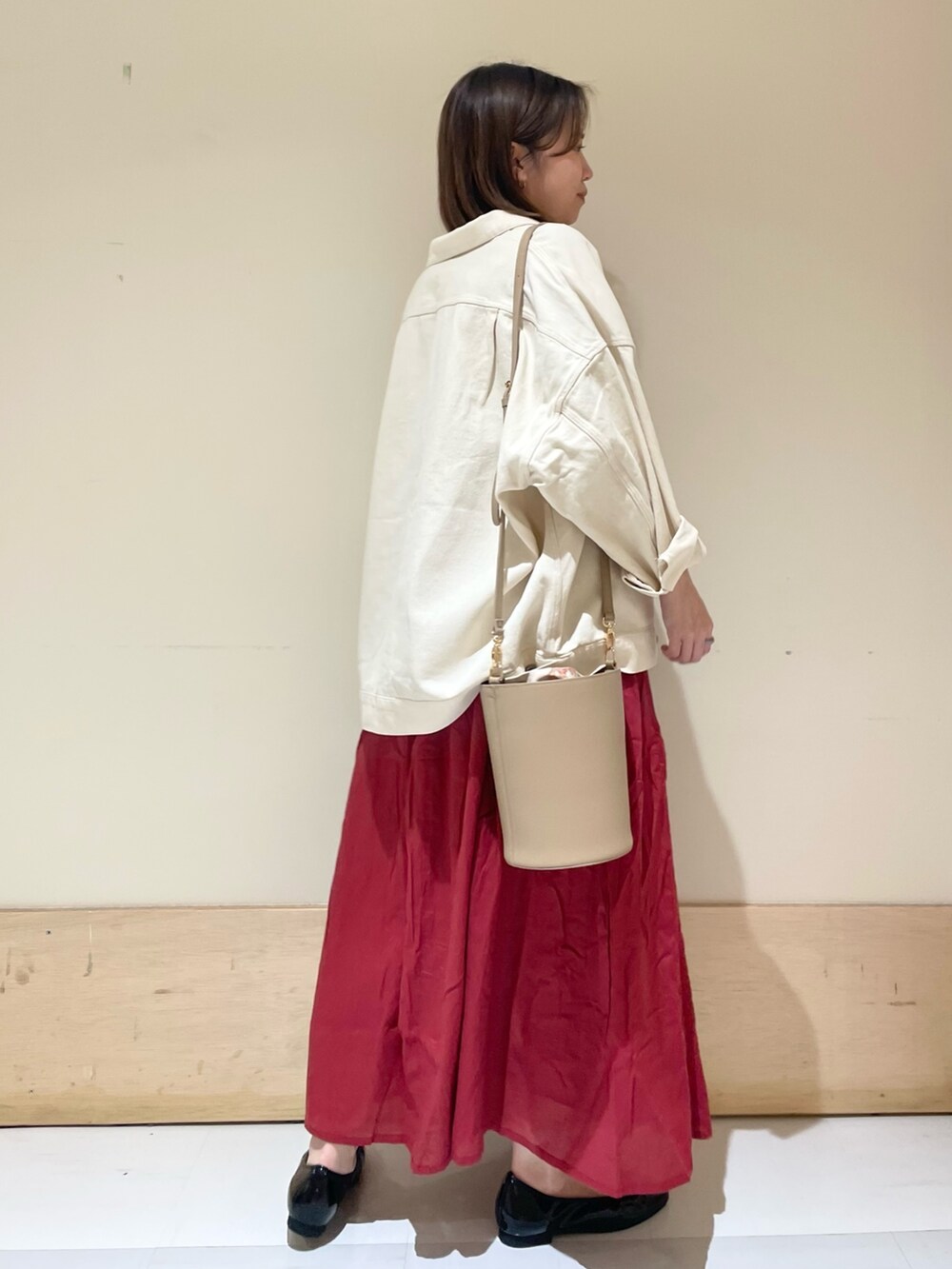 ブラック系のパンプス、ベージュ系のショルダーバッグ、レッド系のワンピースを着用したレディースの秋コーディネートの5枚目の写真