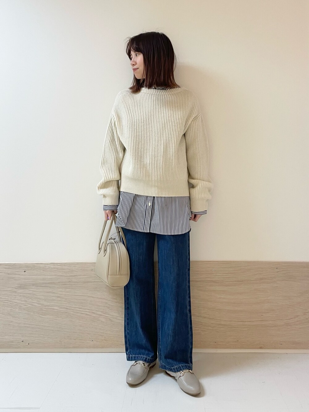 ホワイト系のニット/セーター、ブルー系のデニムパンツ、ベージュ系のボストンバッグを着用したレディースの冬コーディネートの2枚目の写真