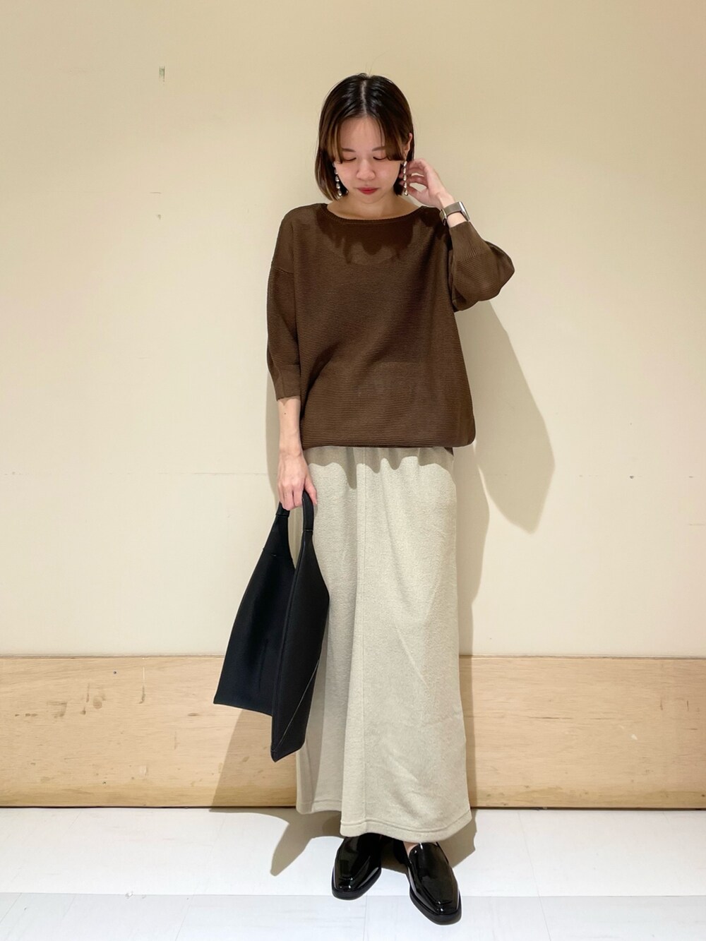 ブラウン系のニット/セーター、ベージュ系のスカート、ブラック系のドレスシューズを着用したレディースの秋コーディネートの3枚目の写真