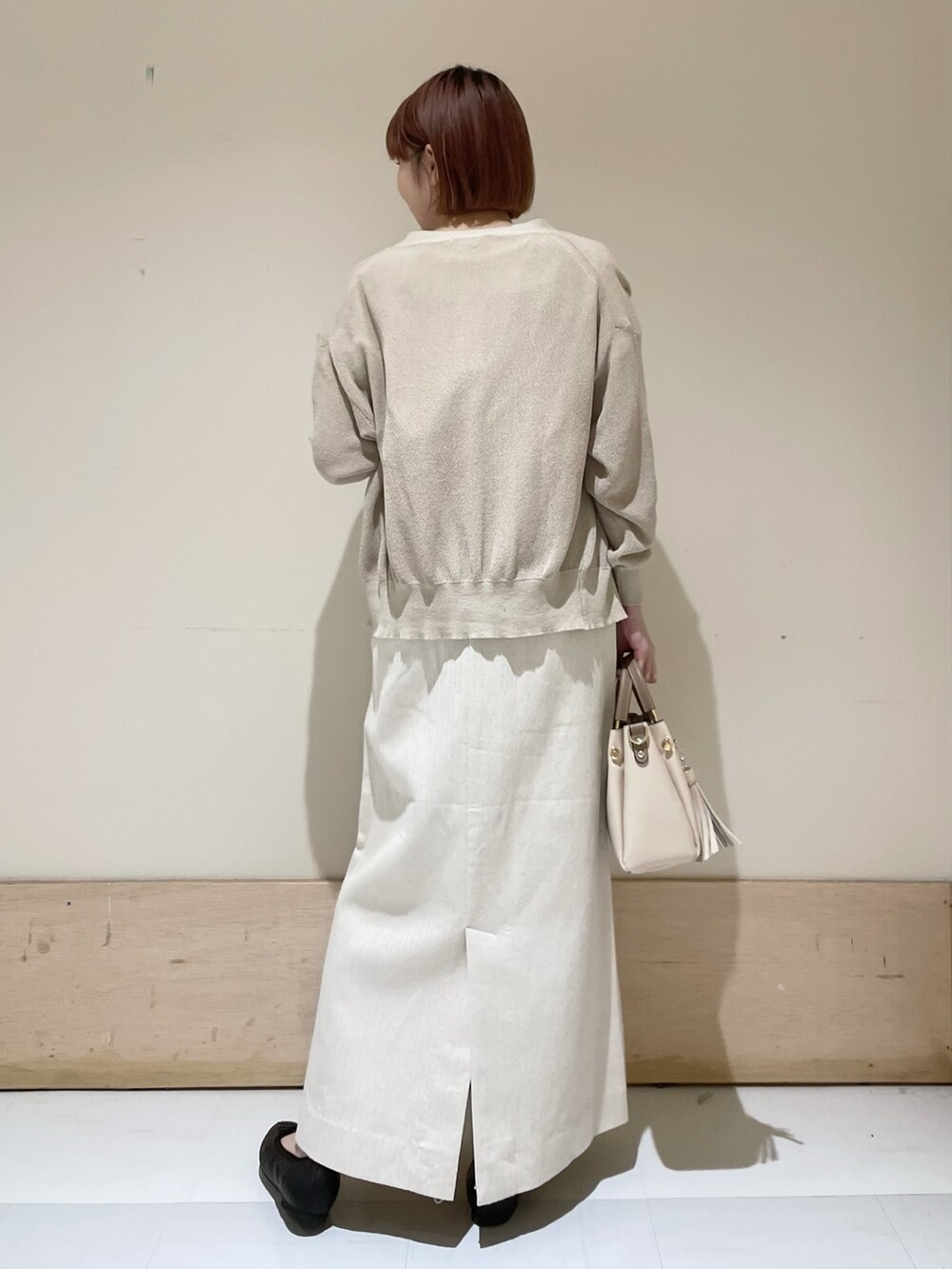 ベージュ系のスカート、ベージュ系のカーディガン/ボレロ、ホワイト系のTシャツ/カットソーを着用したレディースの春コーディネートの6枚目の写真