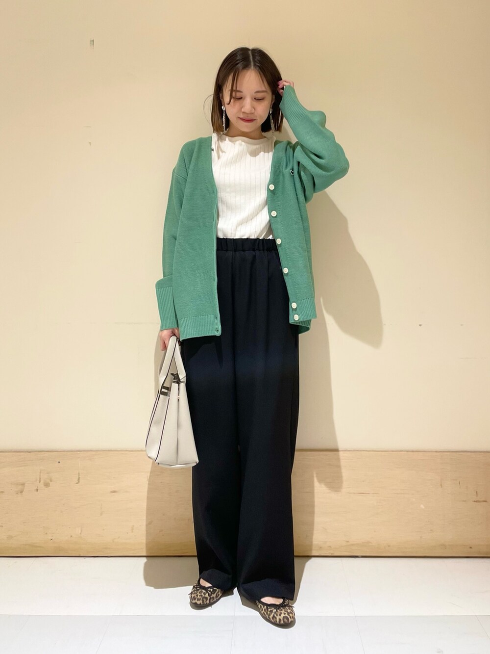 グリーン系のカーディガン/ボレロ、ホワイト系のTシャツ/カットソー、グレー系のトートバッグを着用したレディースの秋コーディネートの3枚目の写真