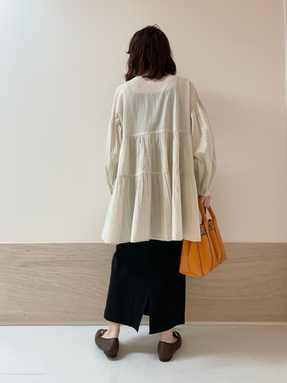 ブラック系のスカート、ホワイト系のチュニックを着用したレディースの春コーディネートの8枚目の写真
