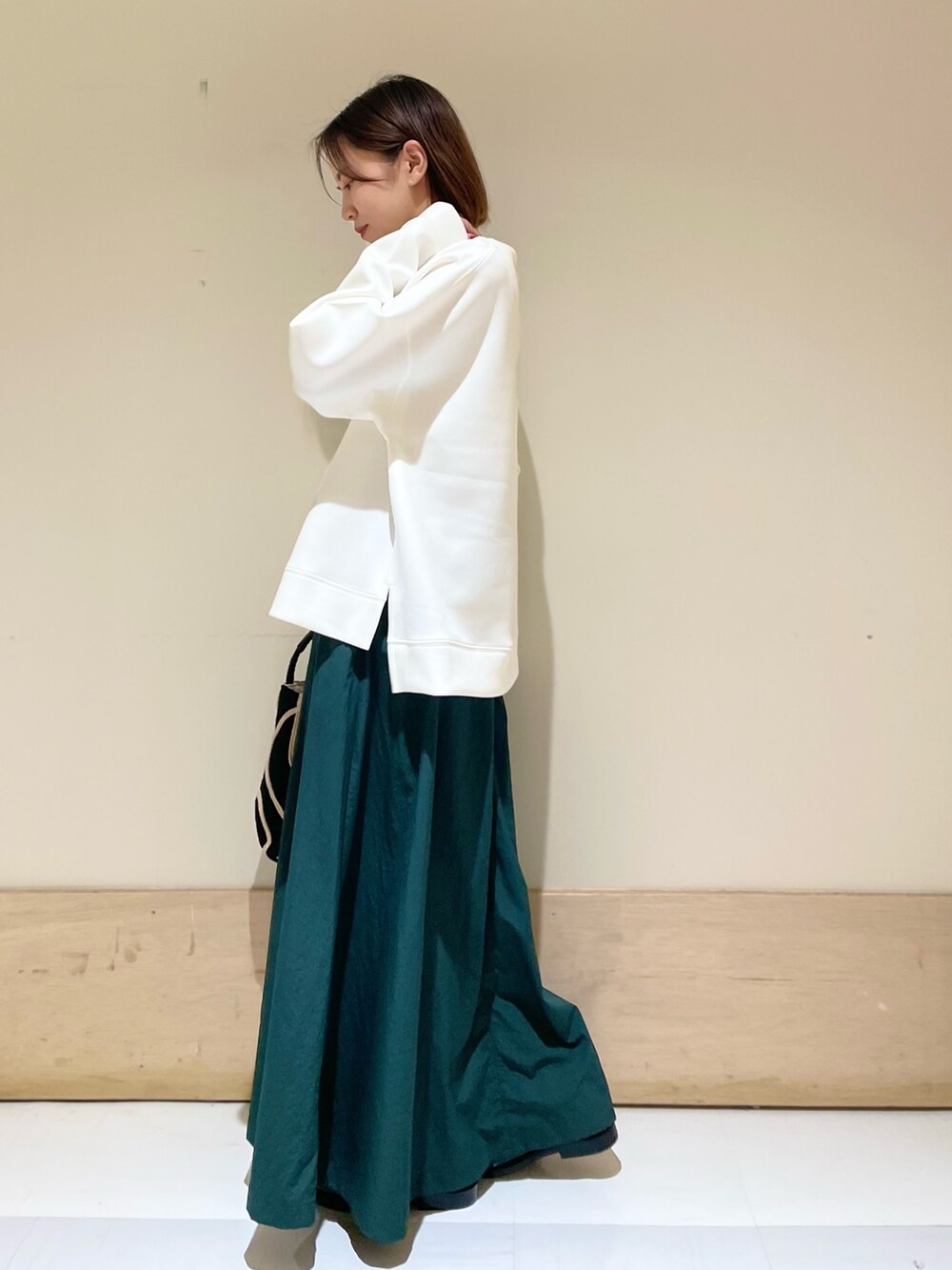 ブラック系のショルダーバッグ、グリーン系のスカート、ブラック系のレインシューズを着用したレディースの秋コーディネートの6枚目の写真