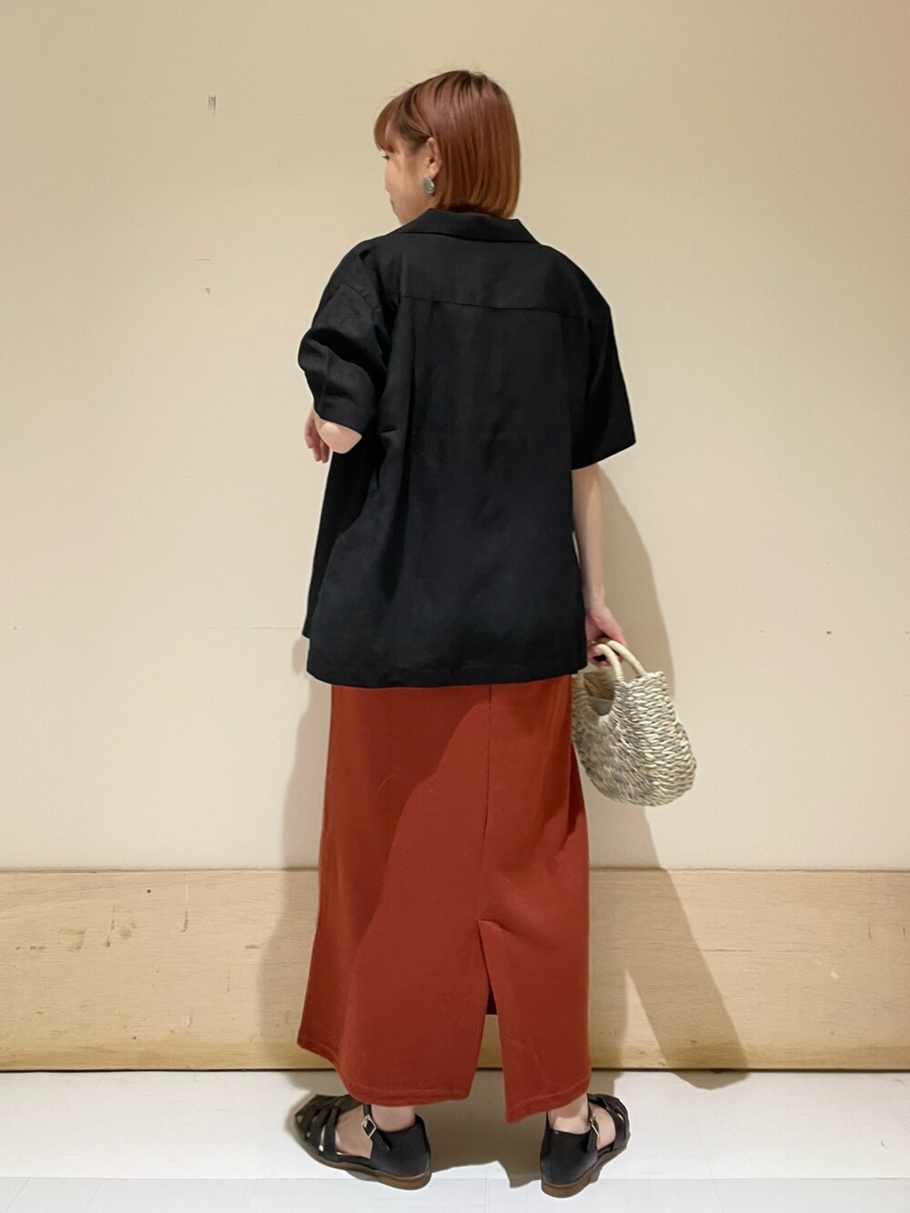 オレンジ系のワンピース、グレー系のかごバッグ、ブラック系のシャツ/ブラウスを着用したレディースの春コーディネートの5枚目の写真