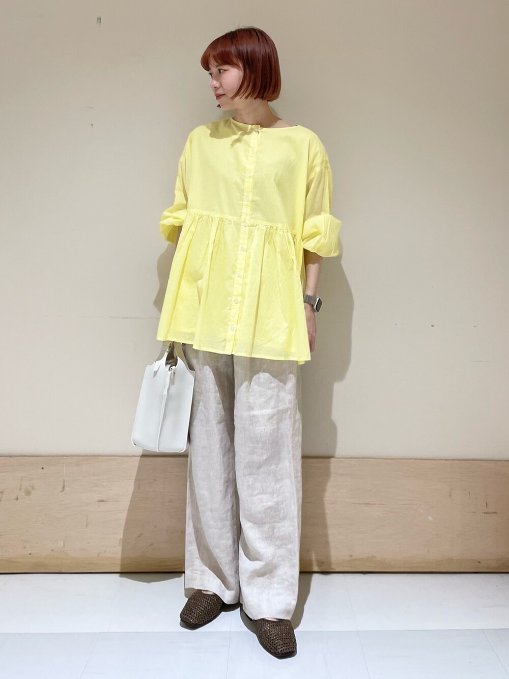 ベージュ系のその他パンツ、イエロー系のシャツ/ブラウス、ホワイト系のトートバッグを着用したレディースの春コーディネートの3枚目の写真