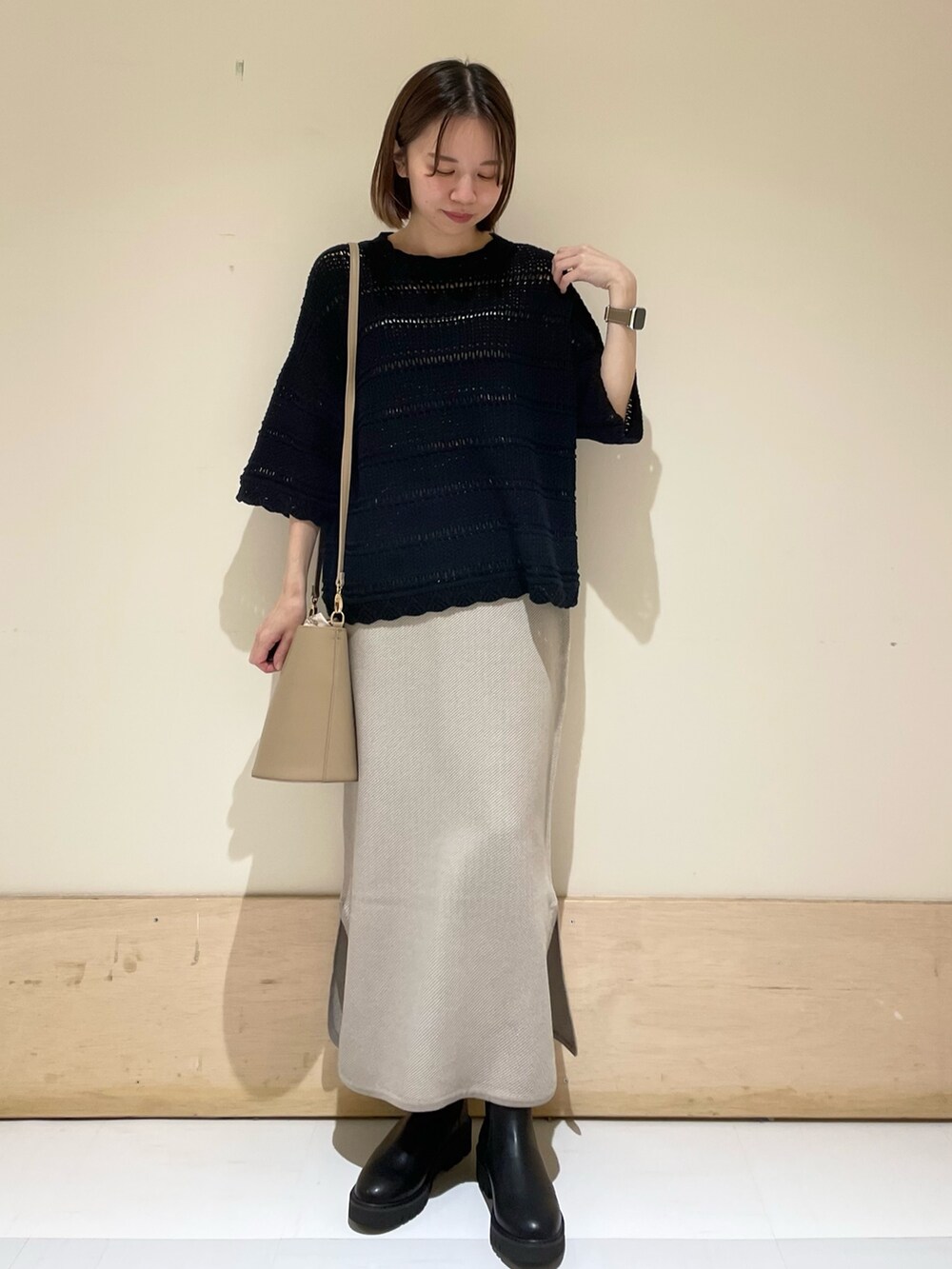 ベージュ系のショルダーバッグ、ブラック系のブーツ、ブラック系のニット/セーターを着用したレディースの秋コーディネートの2枚目の写真