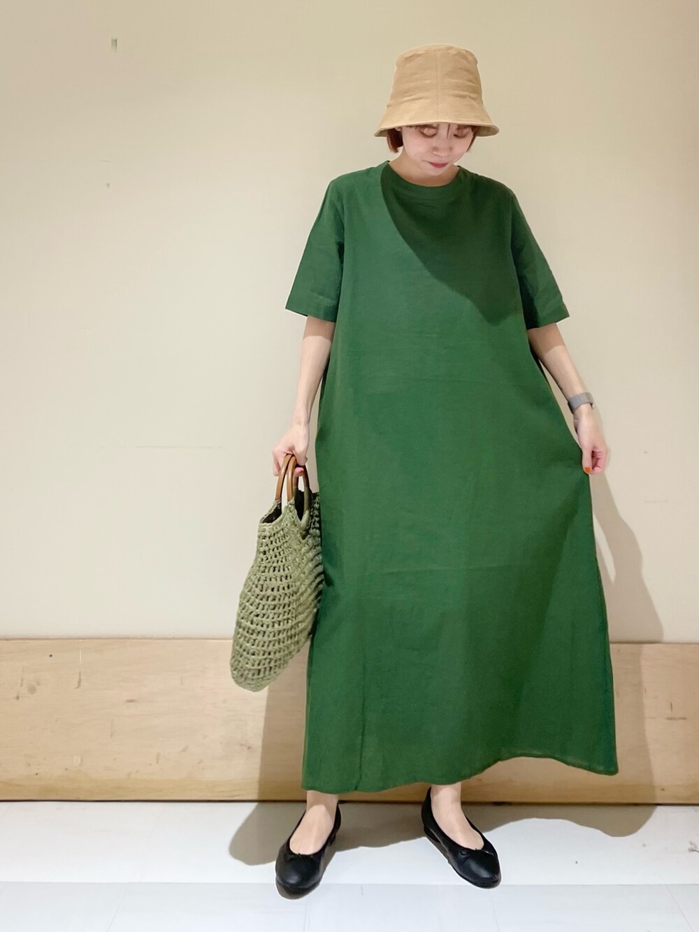 グリーン系のワンピース、ブラック系のバレエシューズ、グリーン系のかごバッグを着用したレディースの春コーディネートの3枚目の写真