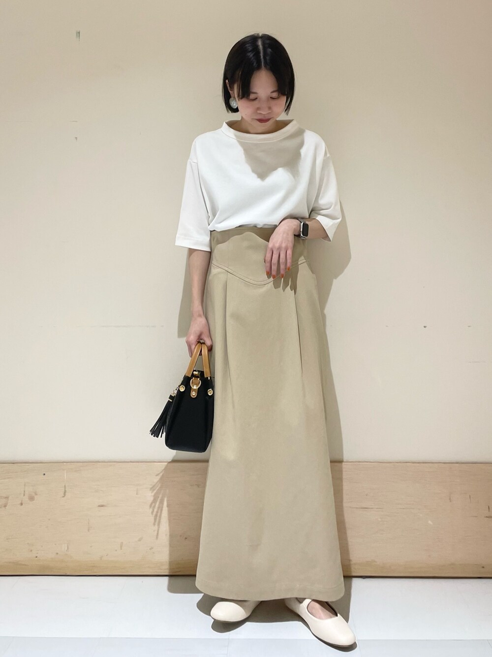 ホワイト系のTシャツ/カットソー、ブラック系のトートバッグ、ベージュ系のスカートを着用したレディースの夏コーディネートの3枚目の写真