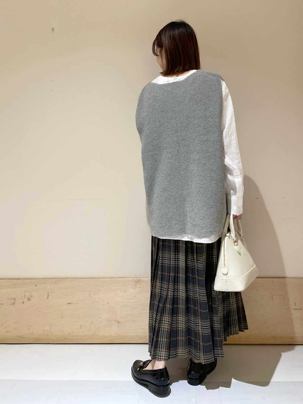 グレー系のベスト、ホワイト系のTシャツ/カットソー、ブラック系のレインシューズを着用したレディースの秋コーディネートの6枚目の写真