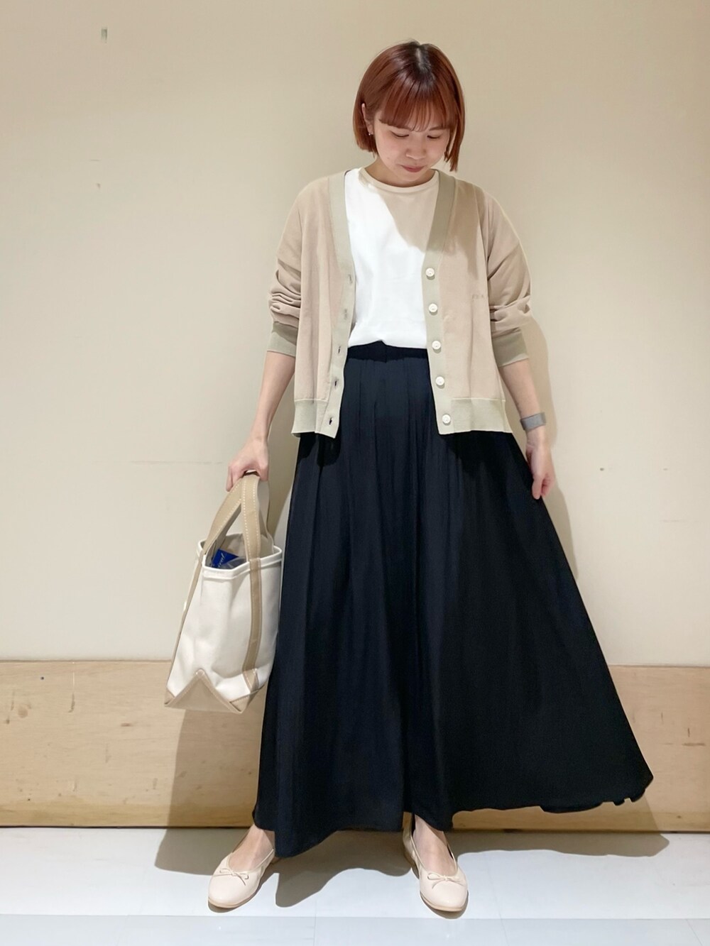 ブラック系のスカート、ベージュ系のカーディガン/ボレロ、ホワイト系のTシャツ/カットソーを着用したレディースの春コーディネートの2枚目の写真