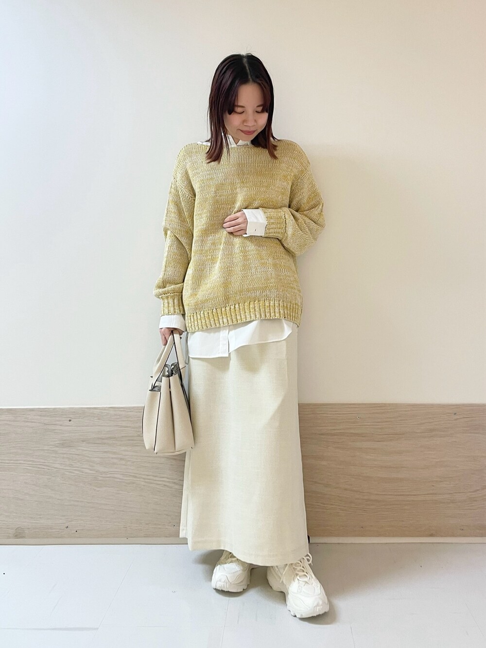 イエロー系のニット/セーター、ホワイト系のシャツ/ブラウス、ホワイト系のスカートを着用したレディースの春コーディネートの3枚目の写真