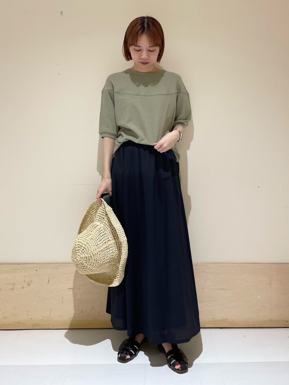 ブルー系のスカート、ブラック系のサンダル、グリーン系のTシャツ/カットソーを着用したレディースの春コーディネートの2枚目の写真