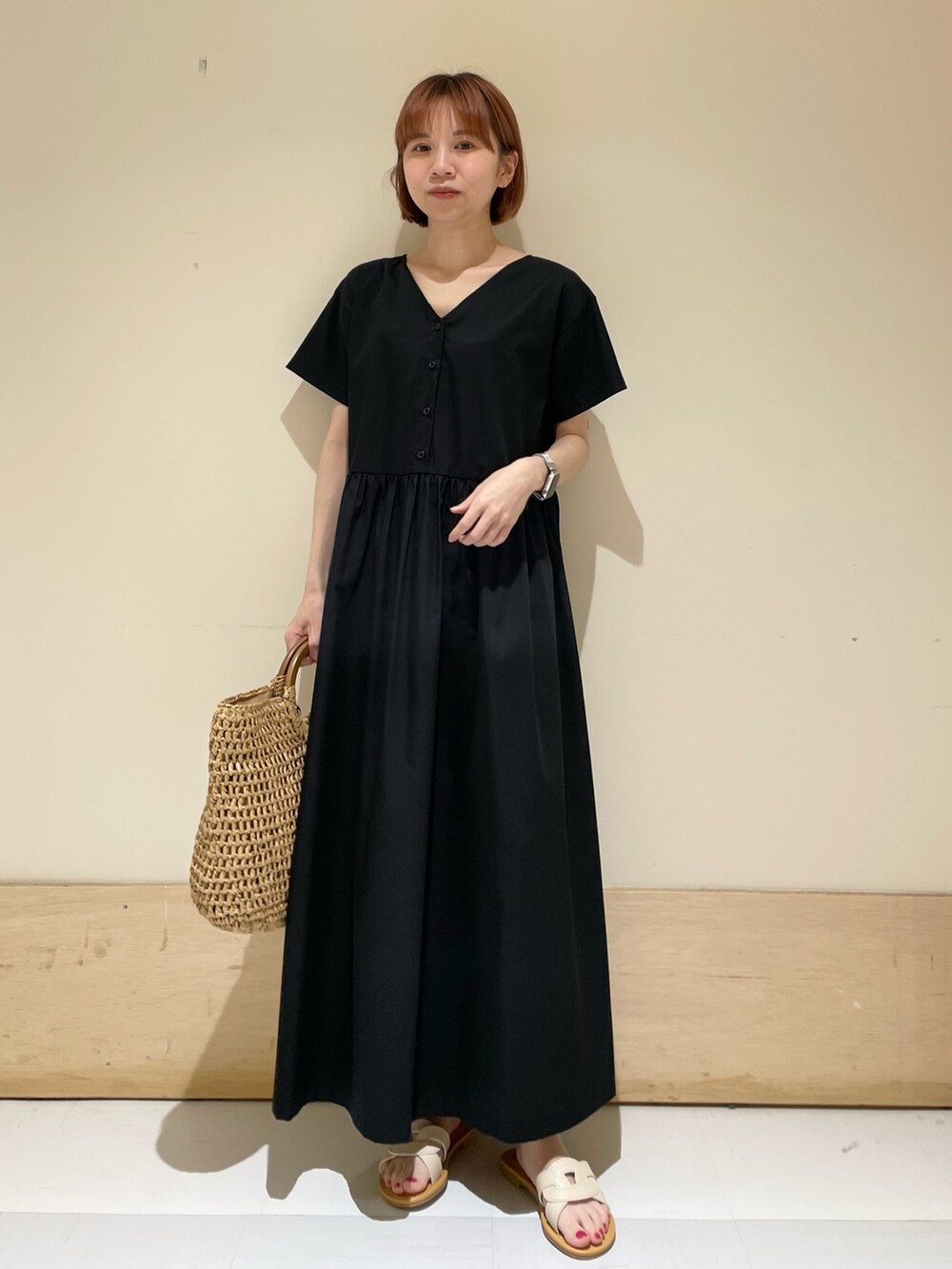 ホワイト系のサンダル、ベージュ系のかごバッグ、ブラック系のワンピースを着用したレディースの春コーディネートの4枚目の写真