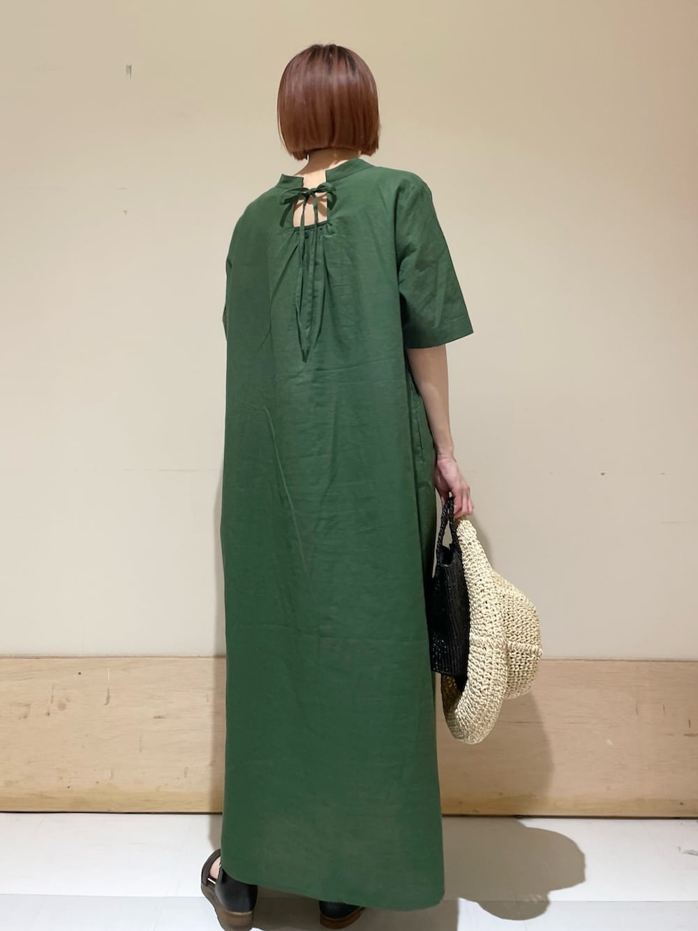 グリーン系のワンピース、ブラック系のサンダル、ブラック系のハンドバッグを着用したレディースの春コーディネートの6枚目の写真