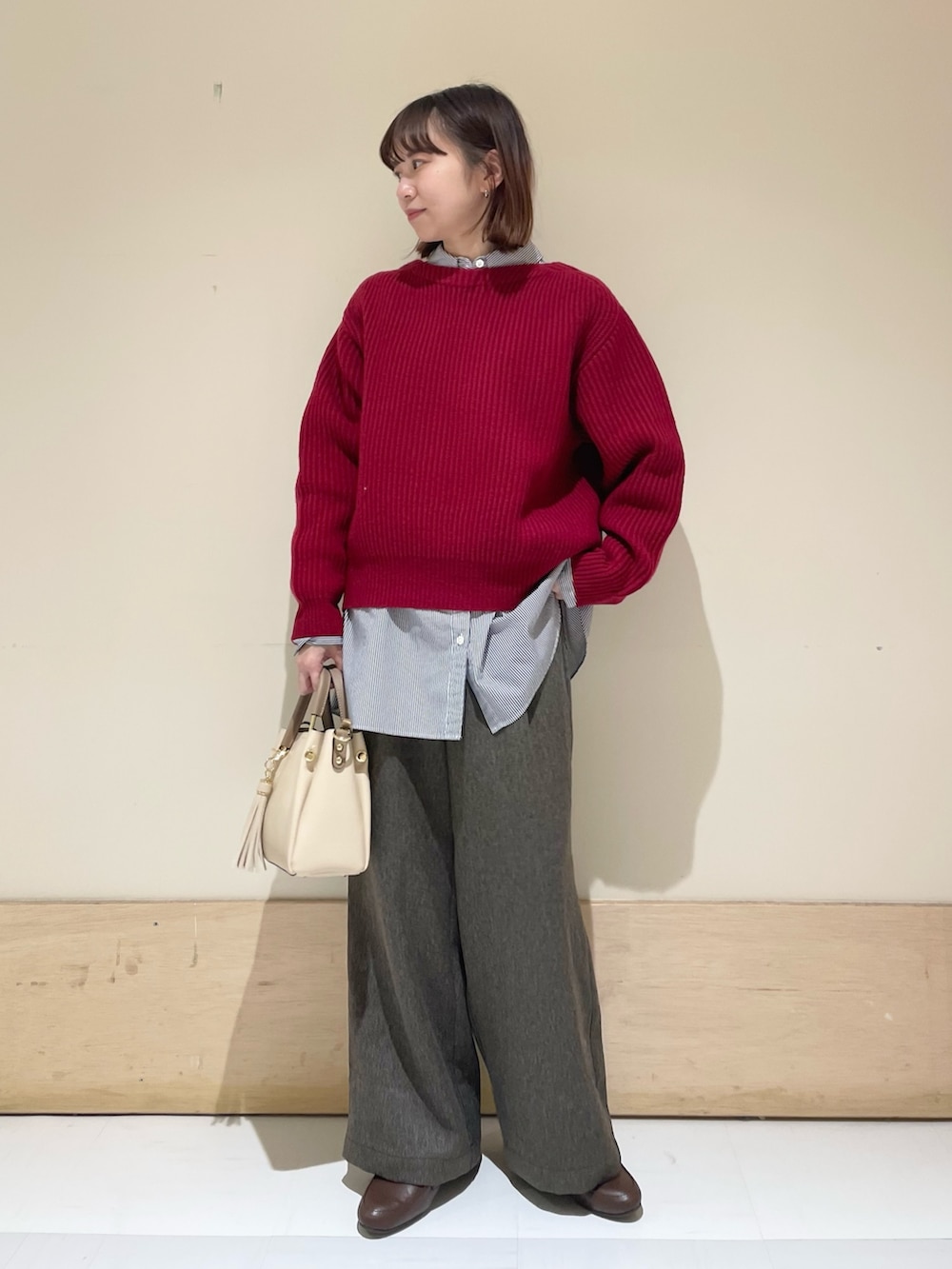 レッド系のニット/セーター、ブラウン系のその他パンツ、ブルー系のシャツ/ブラウスを着用したレディースの冬コーディネートの2枚目の写真