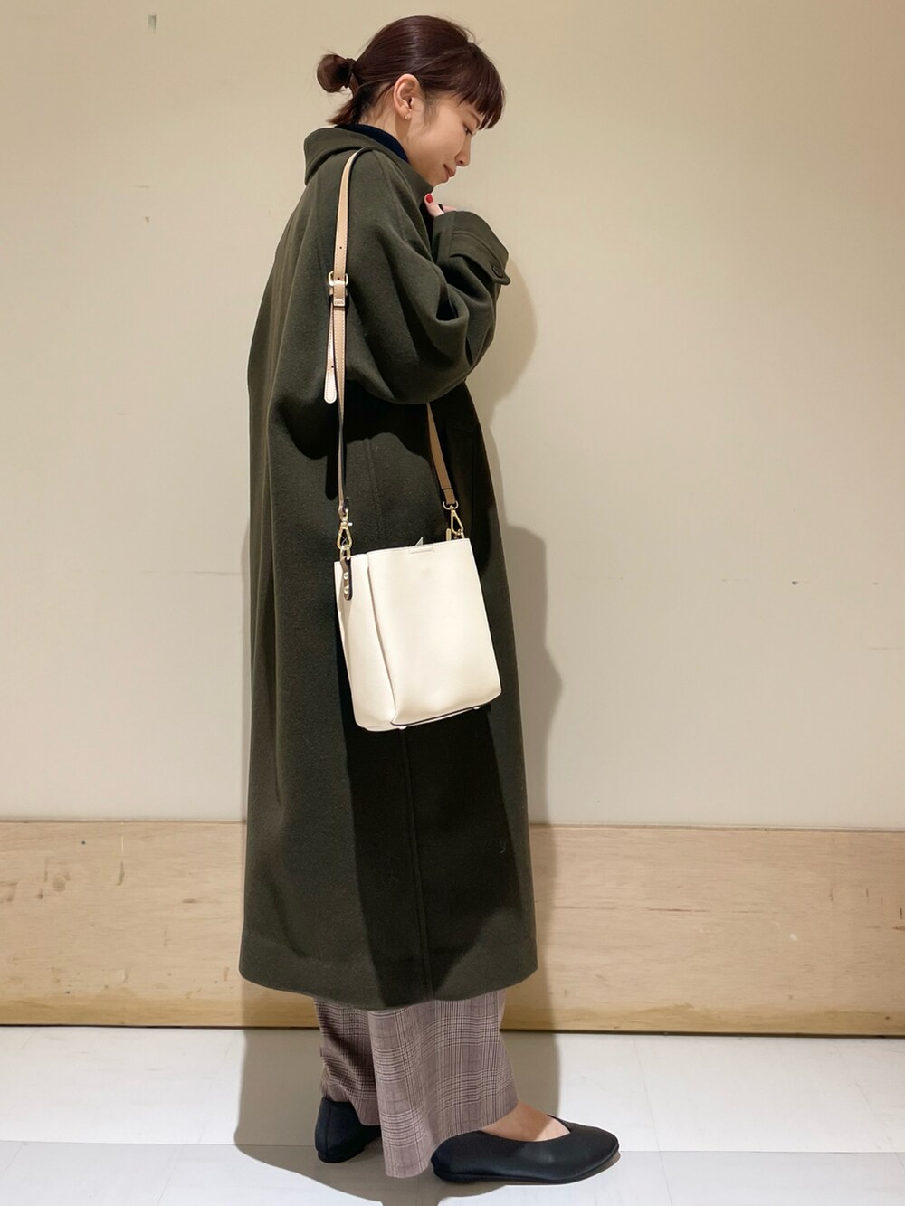 ブルー系のニット/セーター、グリーン系のステンカラーコート、ブラウン系のその他パンツを着用したレディースの冬コーディネートの2枚目の写真