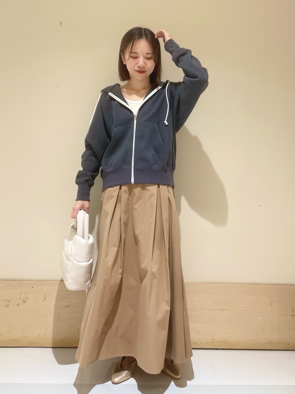 ゴールド系のパンプス、ホワイト系のトートバッグ、ベージュ系のスカートを着用したレディースの秋コーディネートの6枚目の写真