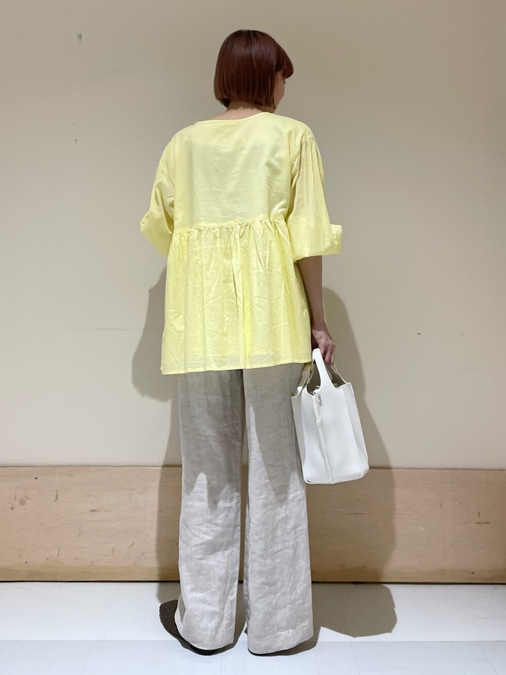 ベージュ系のその他パンツ、イエロー系のシャツ/ブラウス、ホワイト系のトートバッグを着用したレディースの春コーディネートの9枚目の写真