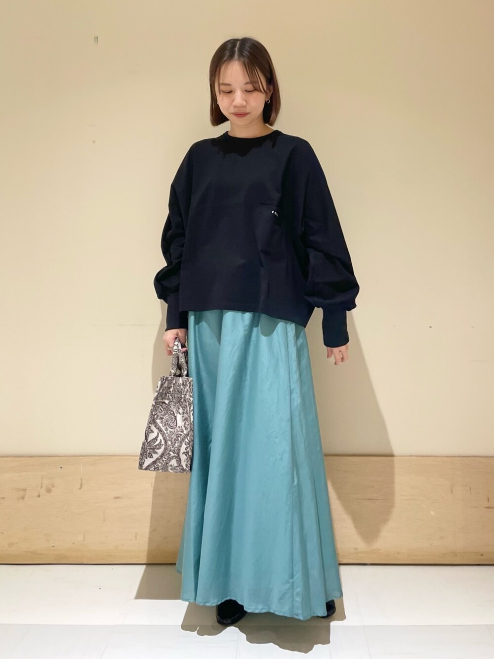 ブラック系のTシャツ/カットソー、グリーン系のスカート、ブラウン系のトートバッグを着用したレディースの秋コーディネートの3枚目の写真