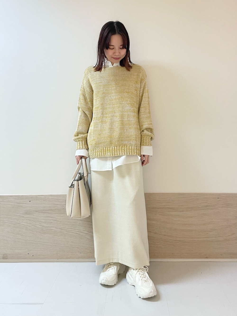 イエロー系のニット/セーター、ホワイト系のシャツ/ブラウス、ホワイト系のスカートを着用したレディースの春コーディネートの4枚目の写真