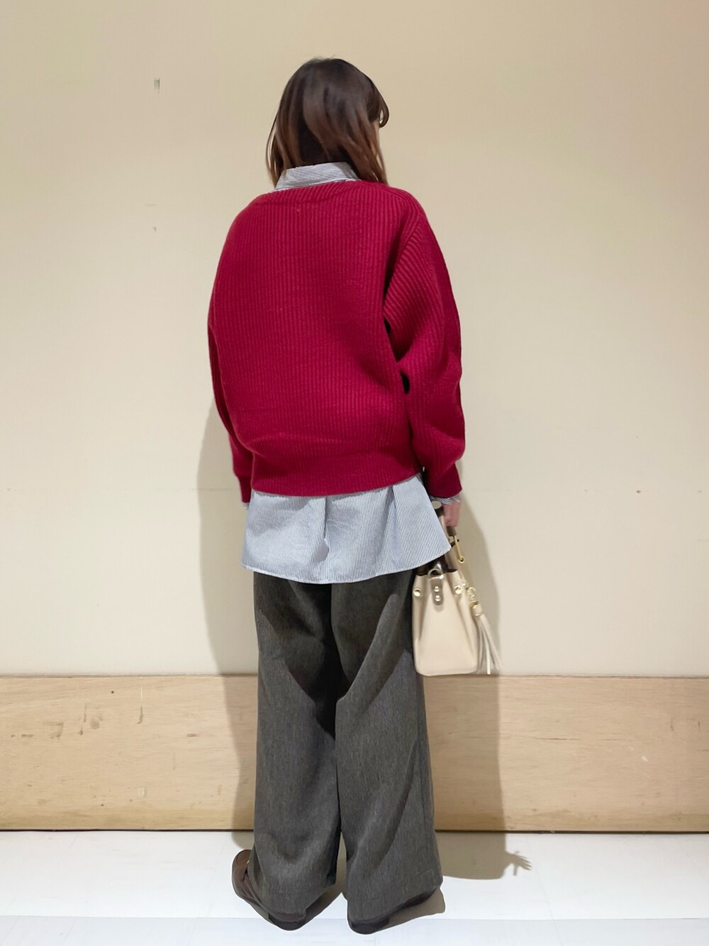 レッド系のニット/セーター、ブラウン系のその他パンツ、ブルー系のシャツ/ブラウスを着用したレディースの冬コーディネートの6枚目の写真