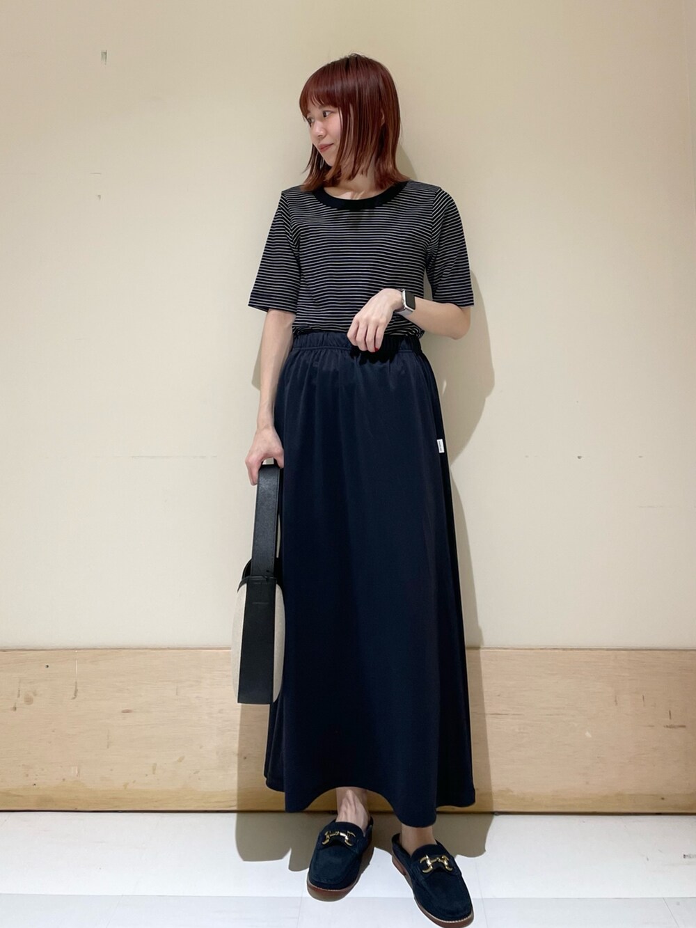 ブルー系のその他シューズ、ブルー系のスカート、ブラック系のハンドバッグを着用したレディースの春コーディネートの2枚目の写真