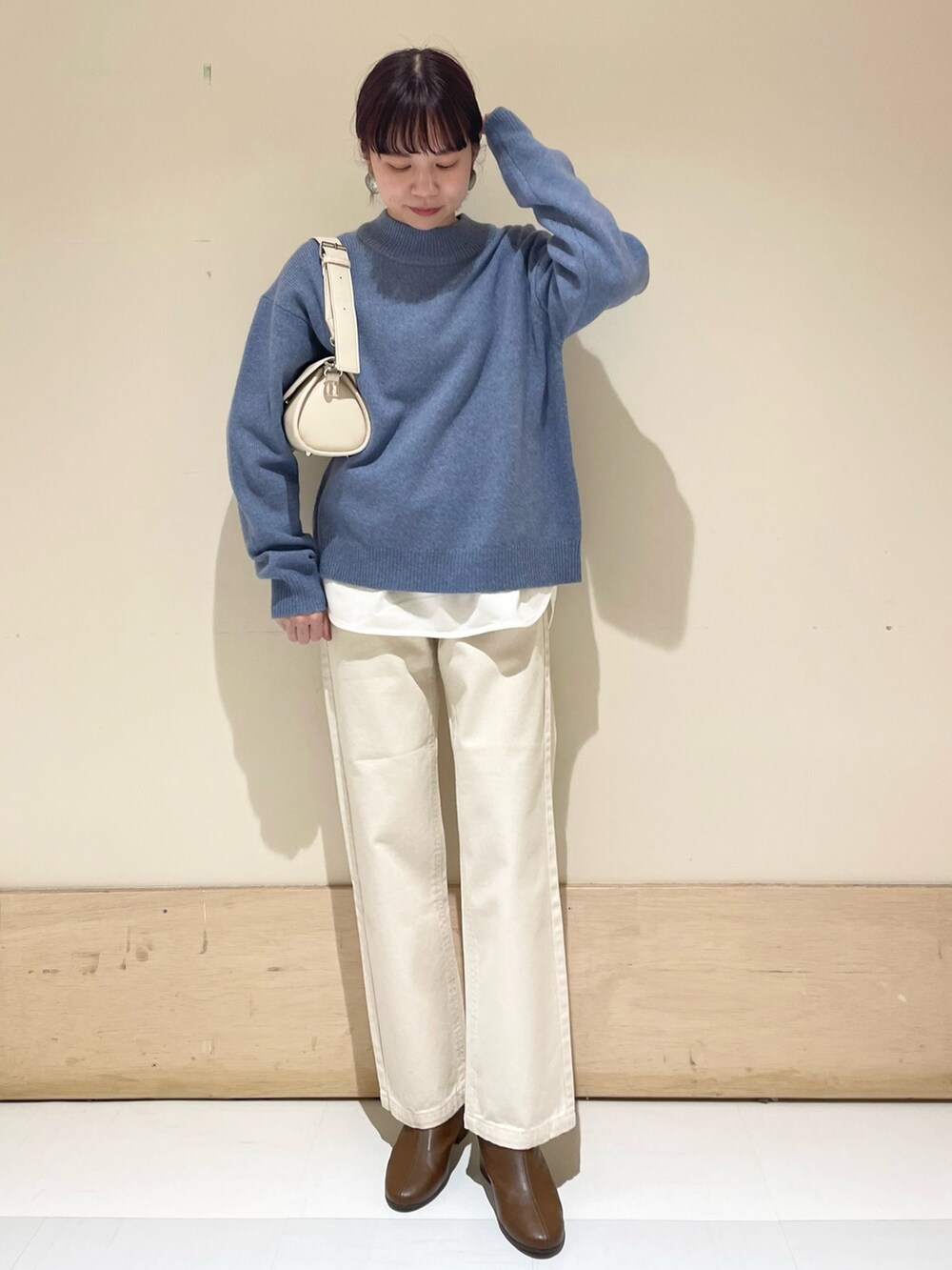 ベージュ系のデニムパンツ、ブルー系のニット/セーター、ホワイト系のショルダーバッグを着用したレディースの冬コーディネートの3枚目の写真