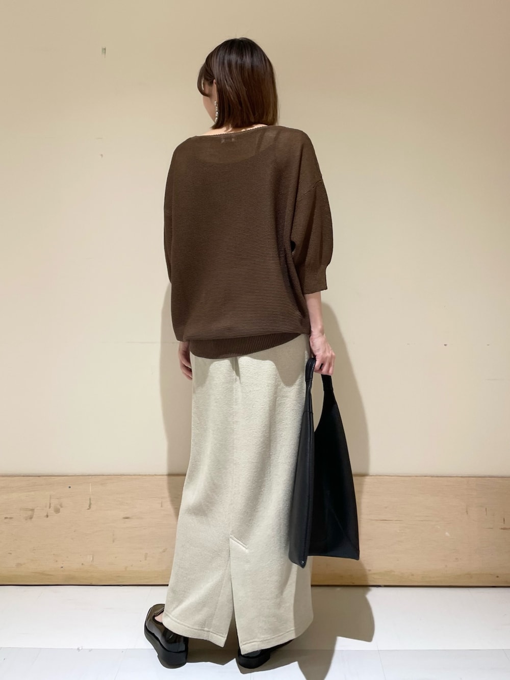 ブラウン系のニット/セーター、ベージュ系のスカート、ブラック系のドレスシューズを着用したレディースの秋コーディネートの7枚目の写真