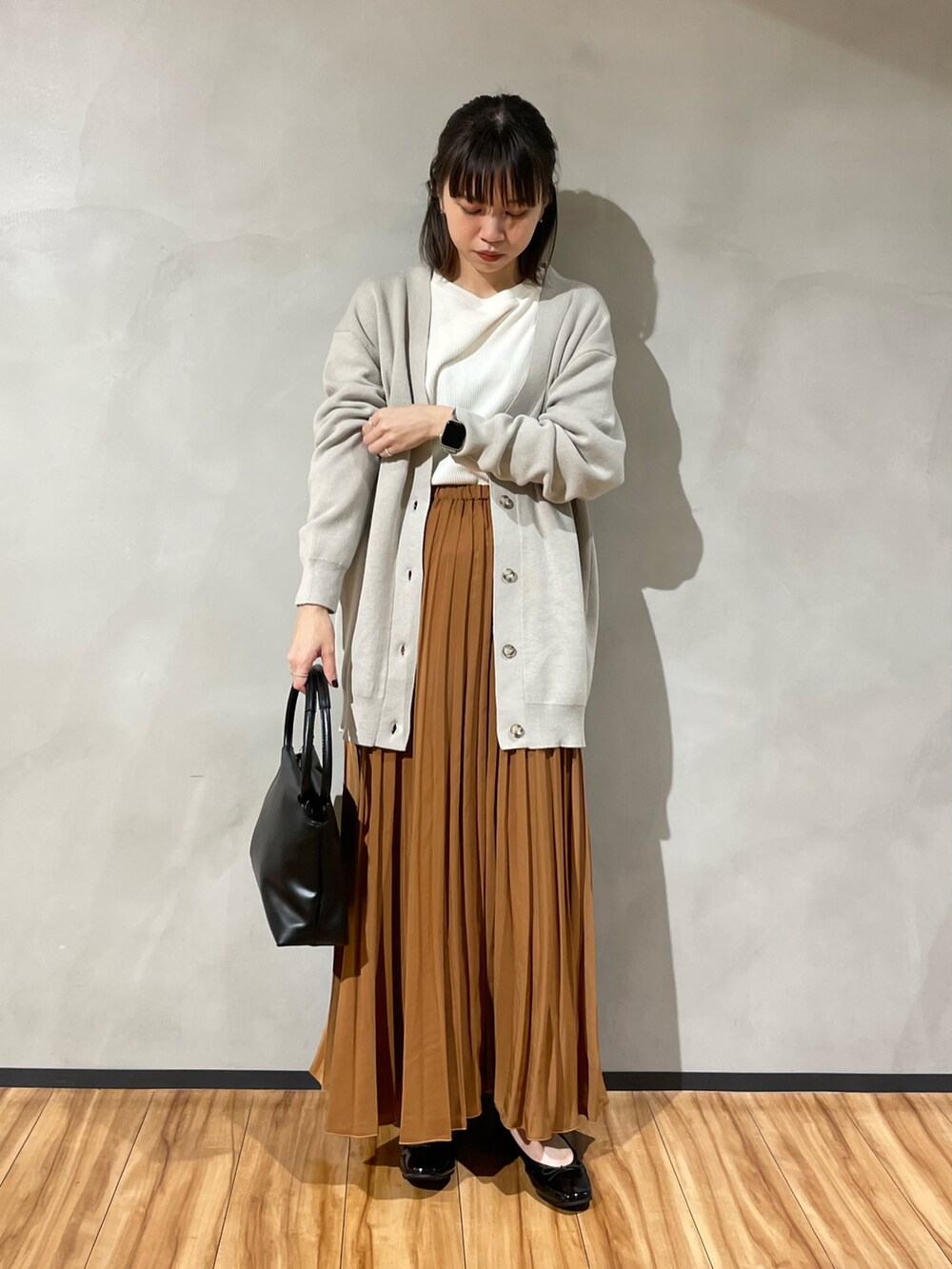 ブラック系のハンドバッグ、イエロー系のスカート、ホワイト系のTシャツ/カットソーを着用したレディースの秋コーディネートの2枚目の写真