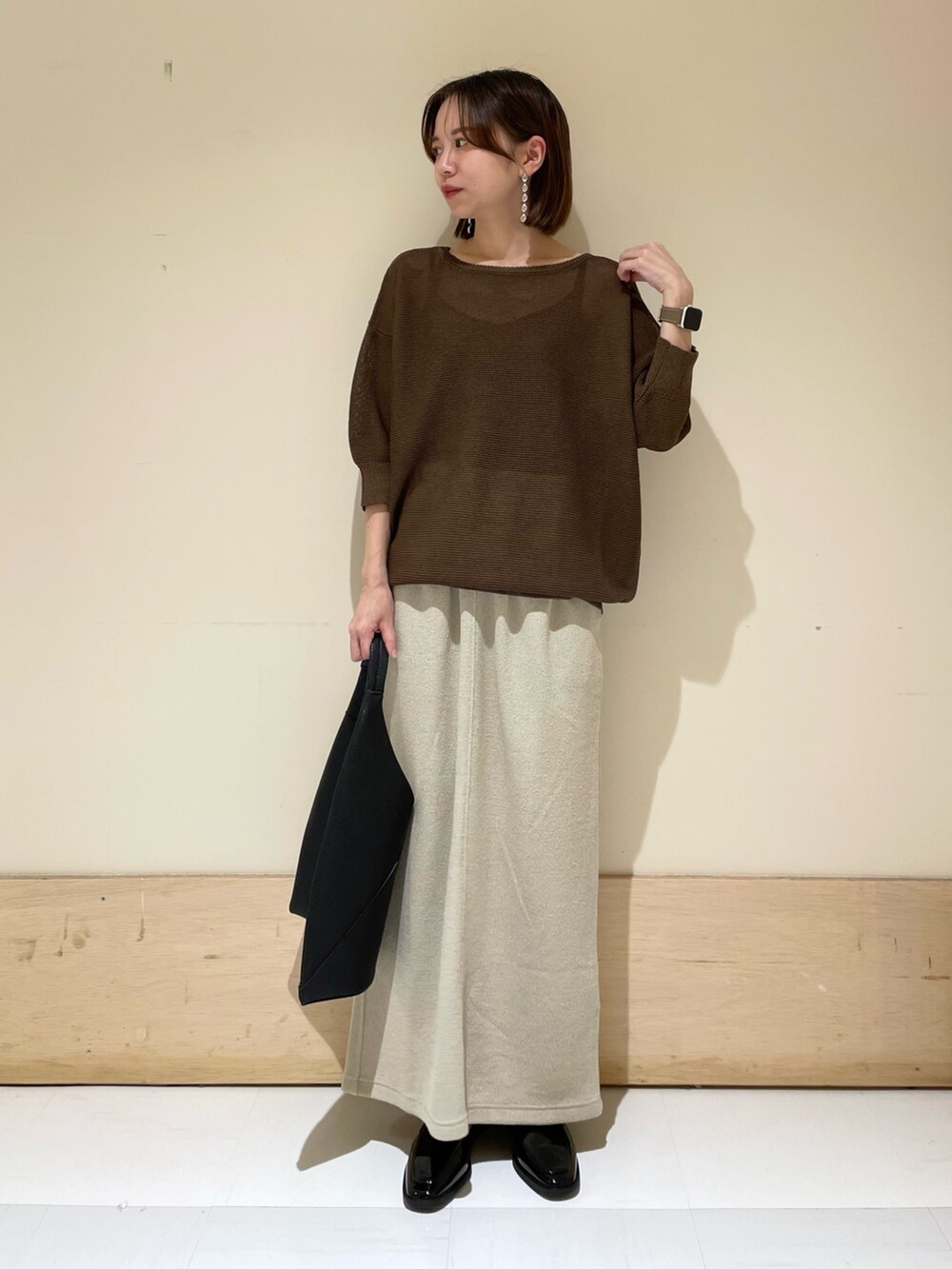 ブラウン系のニット/セーター、ベージュ系のスカート、ブラック系のドレスシューズを着用したレディースの秋コーディネートの4枚目の写真