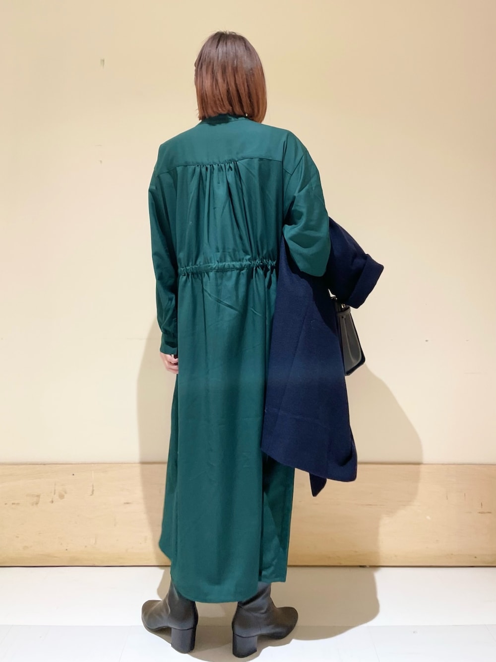 グリーン系のワンピース、ブルー系のピーコート、ブラック系のブーツを着用したレディースの冬コーディネートの10枚目の写真