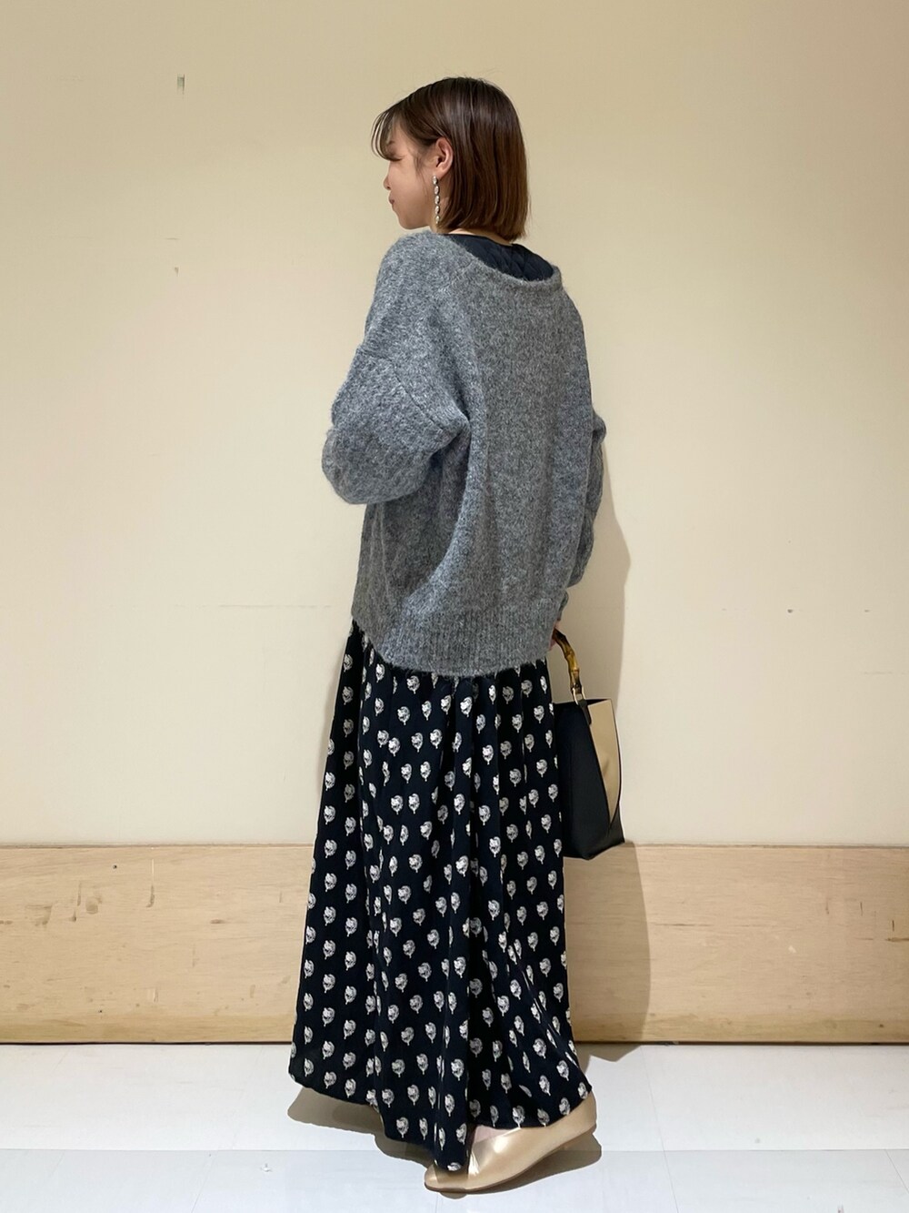 グレー系のニット/セーター、ブラック系のワンピース、ブラック系のハンドバッグを着用したレディースの秋コーディネートの4枚目の写真