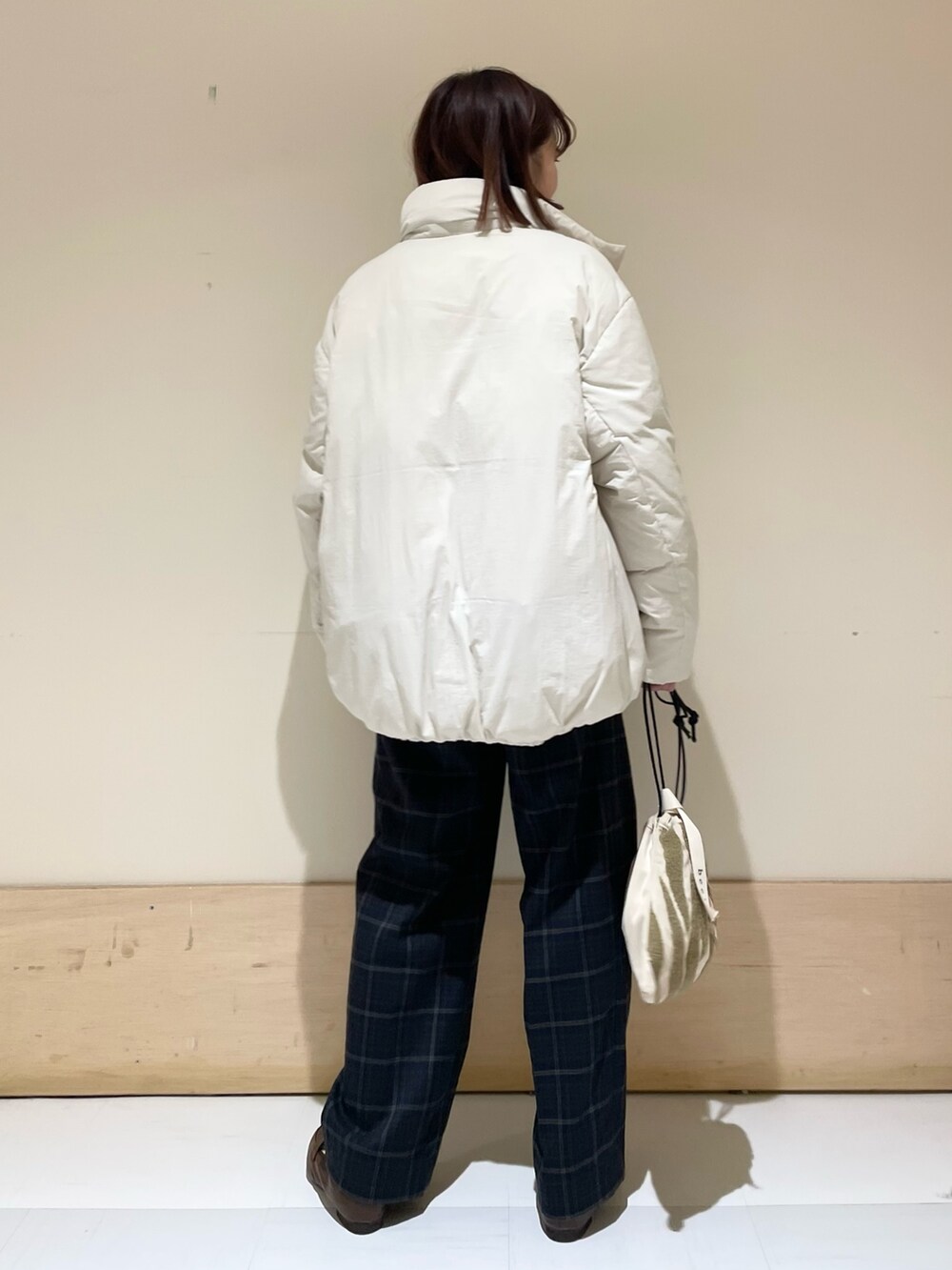 グリーン系のニット/セーター、ホワイト系のダウンジャケット/コート、ブラウン系のローファーを着用したレディースの秋コーディネートの6枚目の写真