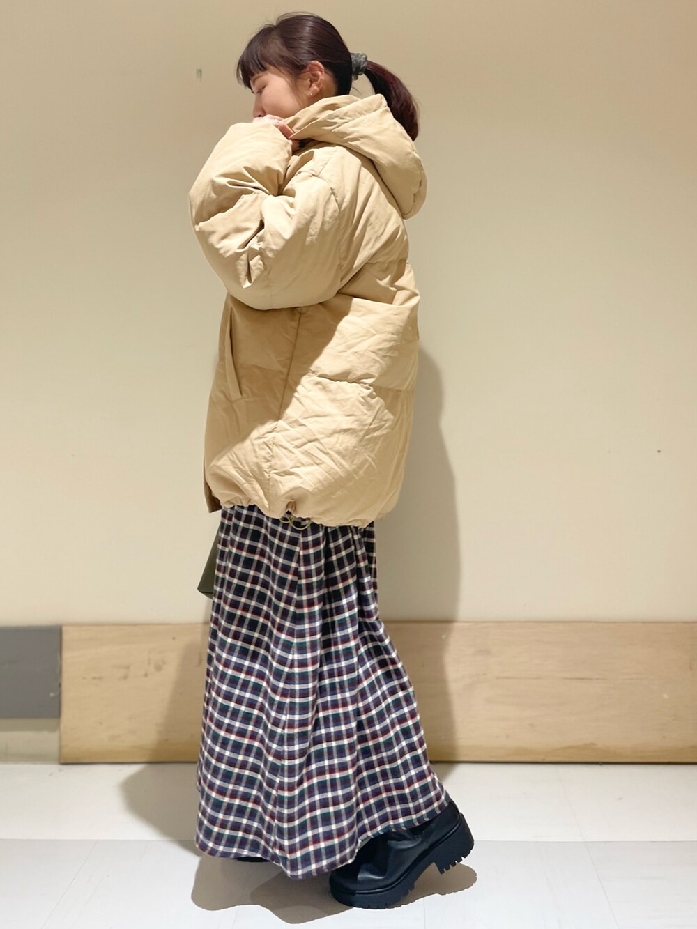 ブラウン系のワンピース、ベージュ系のダウンジャケット/コート、ブラック系のブーツを着用したレディースの冬コーディネートの2枚目の写真