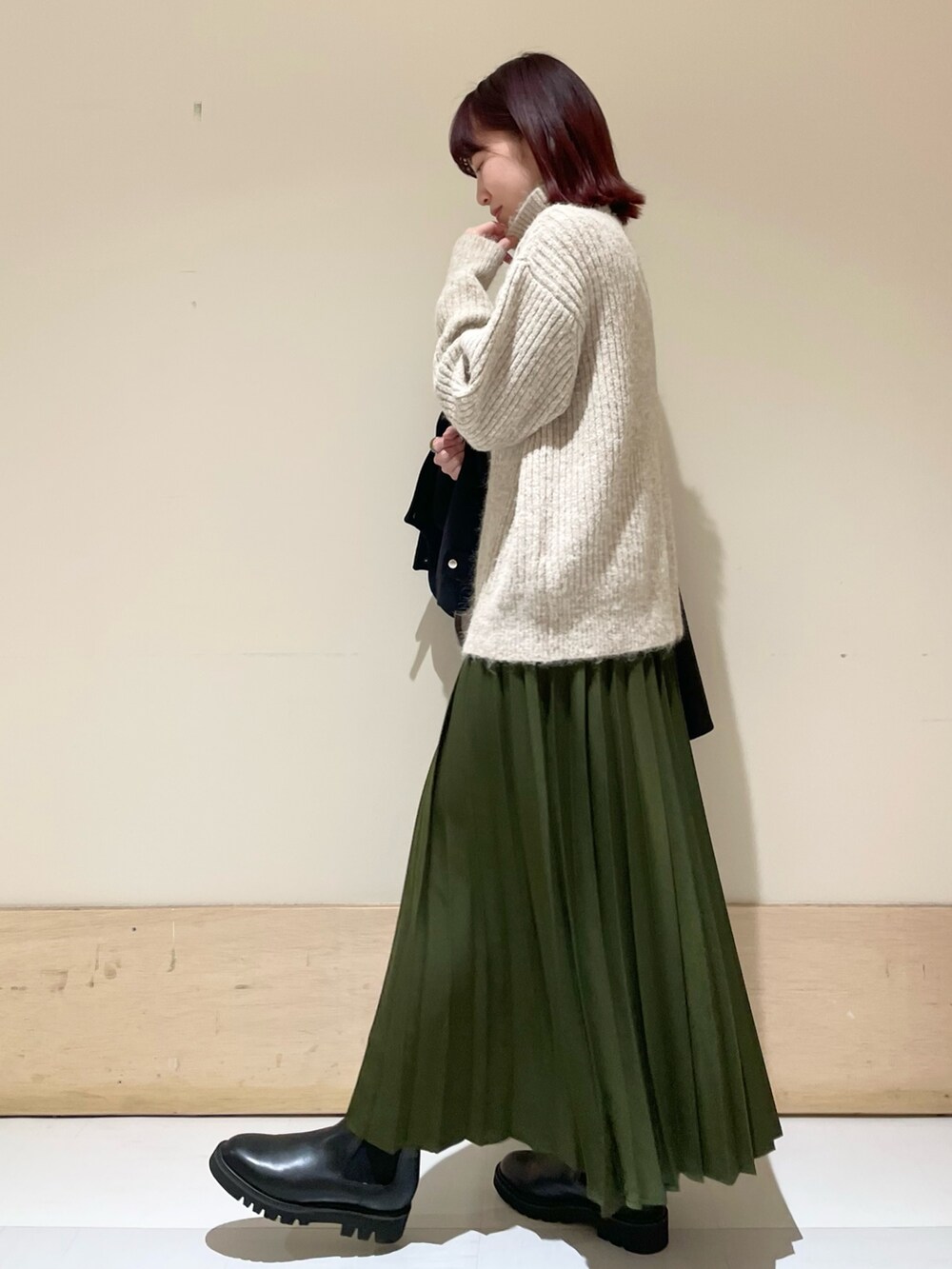 ブラック系のその他アウター、ブラック系のブーツ、グリーン系のスカートを着用したレディースの冬コーディネートの8枚目の写真